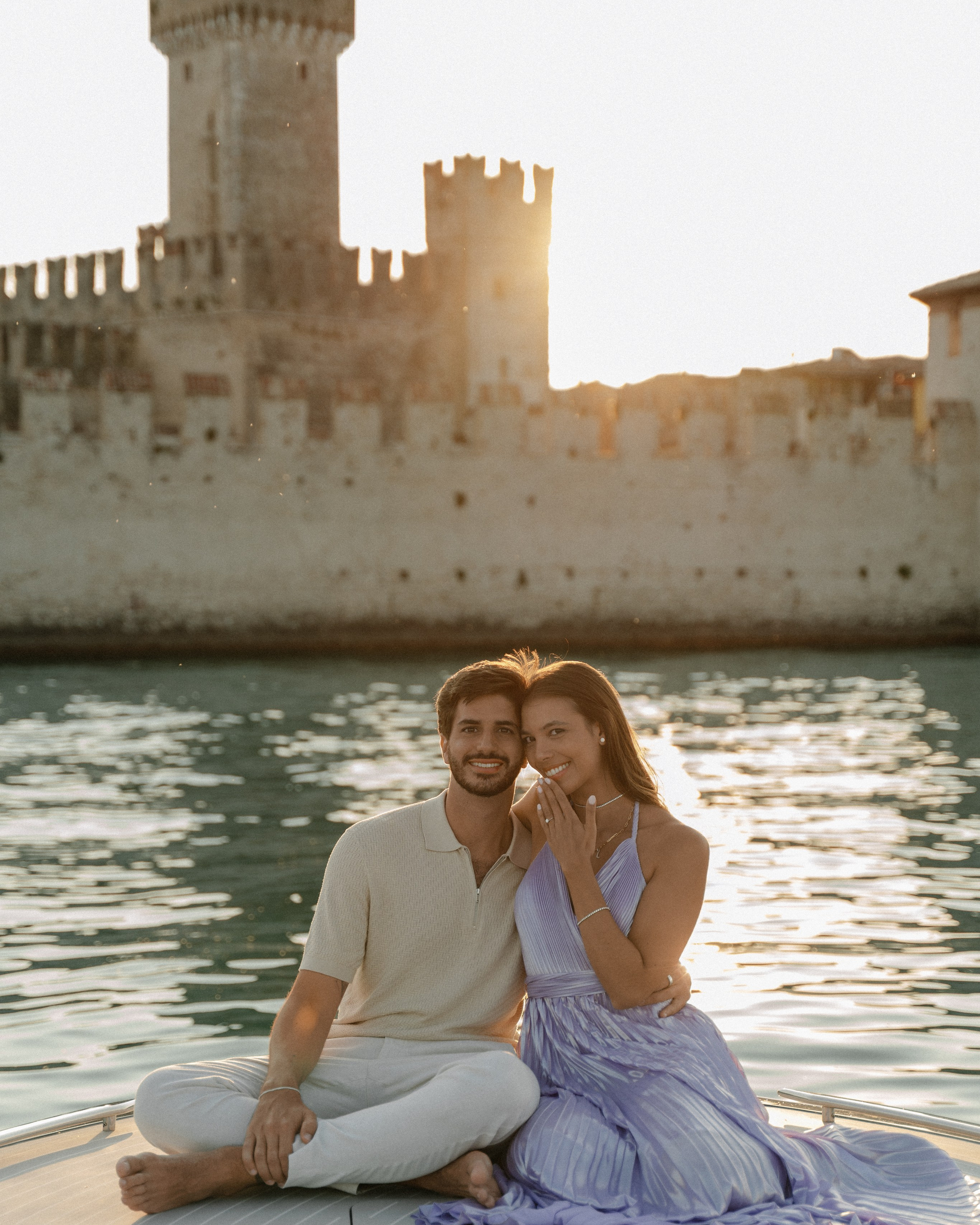 Marriage proposal at Lake Garda on a wooden boat at sunset with the castle of sirmione in the background