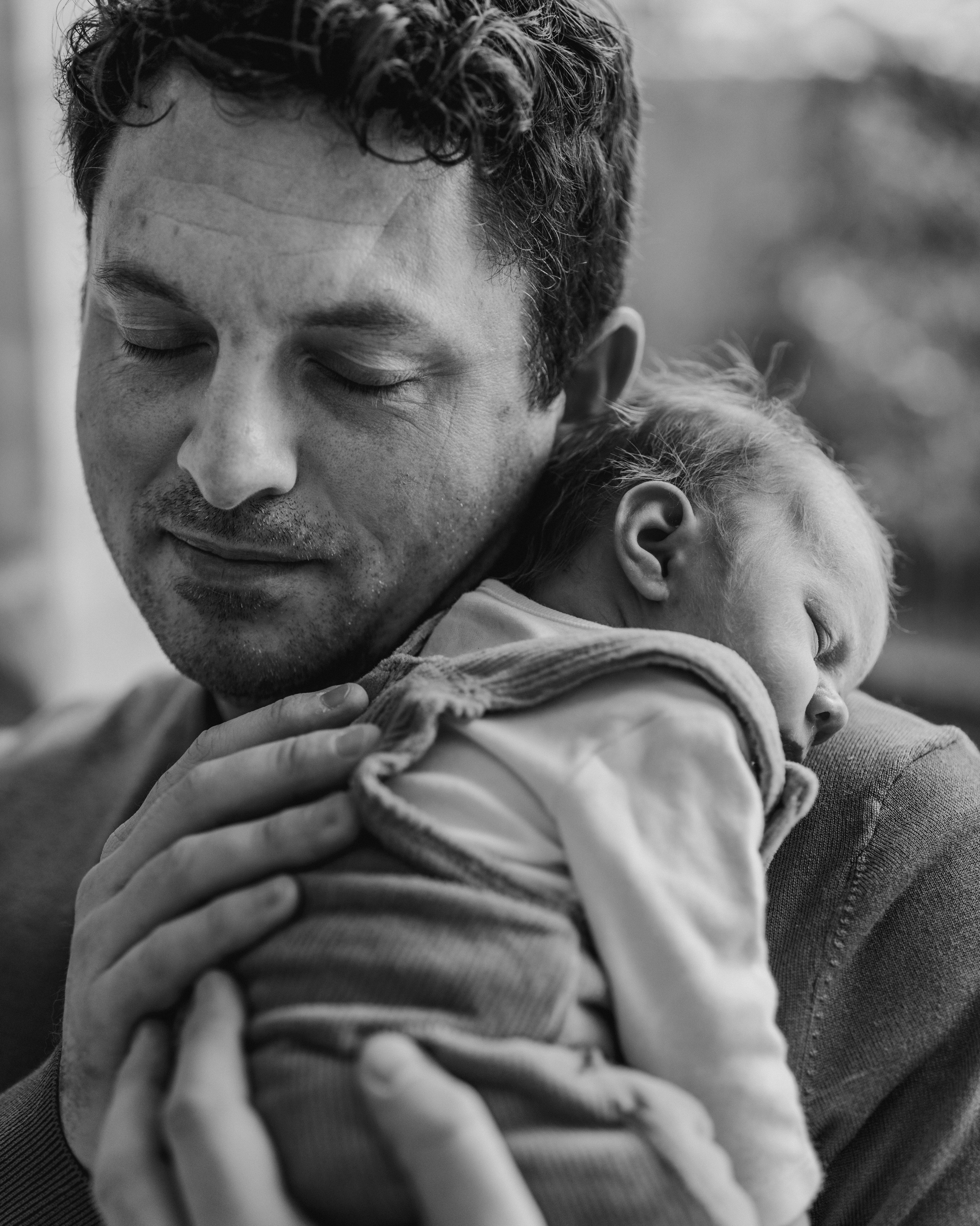 Newborn photographer in Newcastle upon Tyne capturing a father cuddling his baby at home.