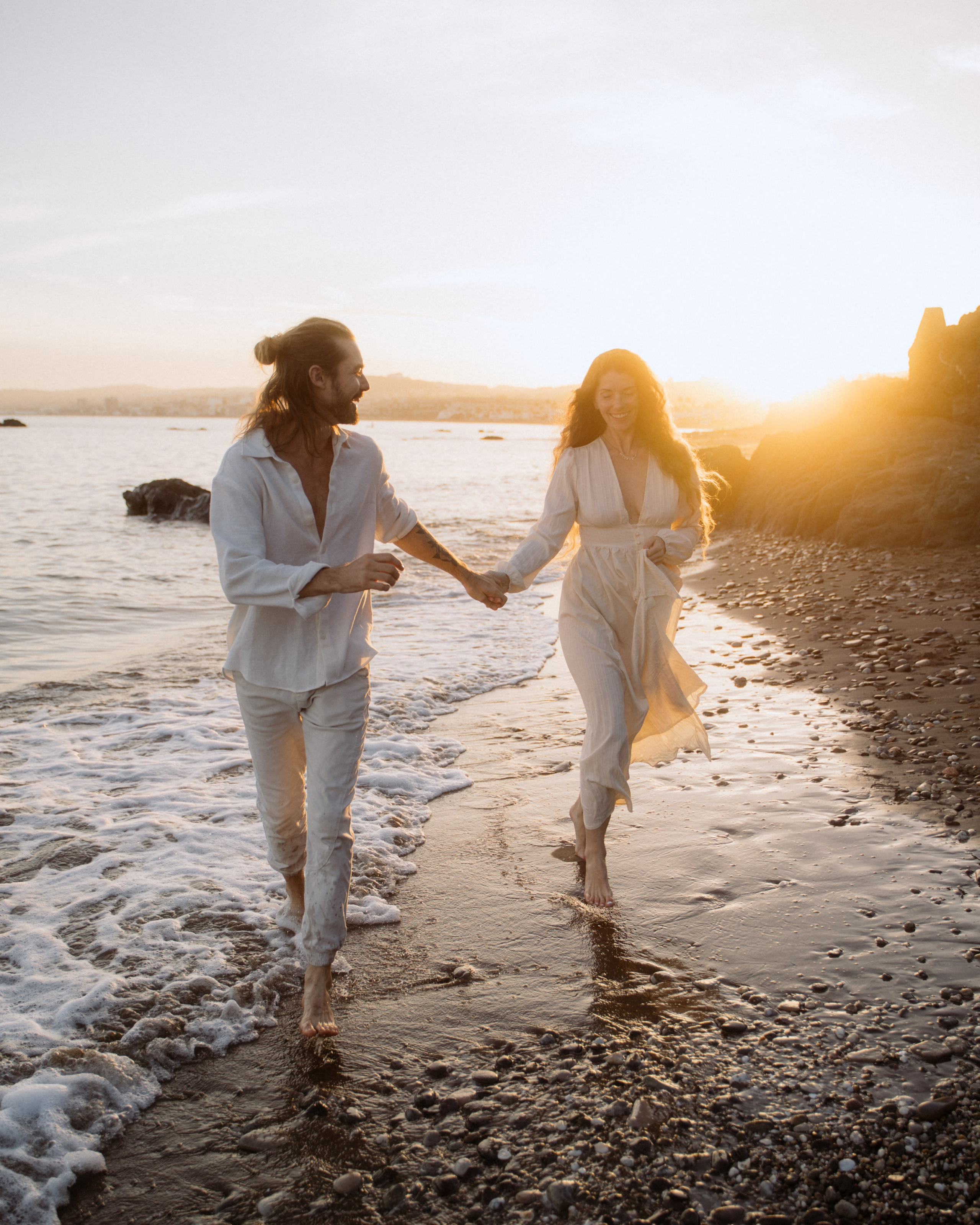 Couple walking hand-in-hand along the shoreline during golden hour