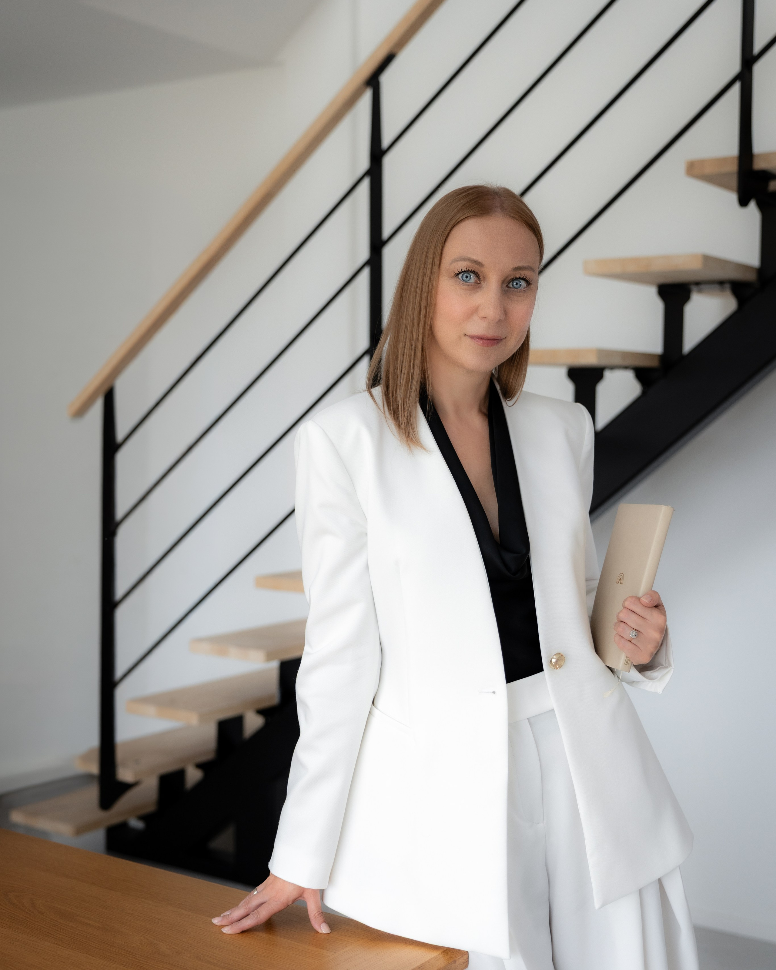 Woman in white blazer and dress on a staircase by black railing, personal brand portrait, Toulouse session