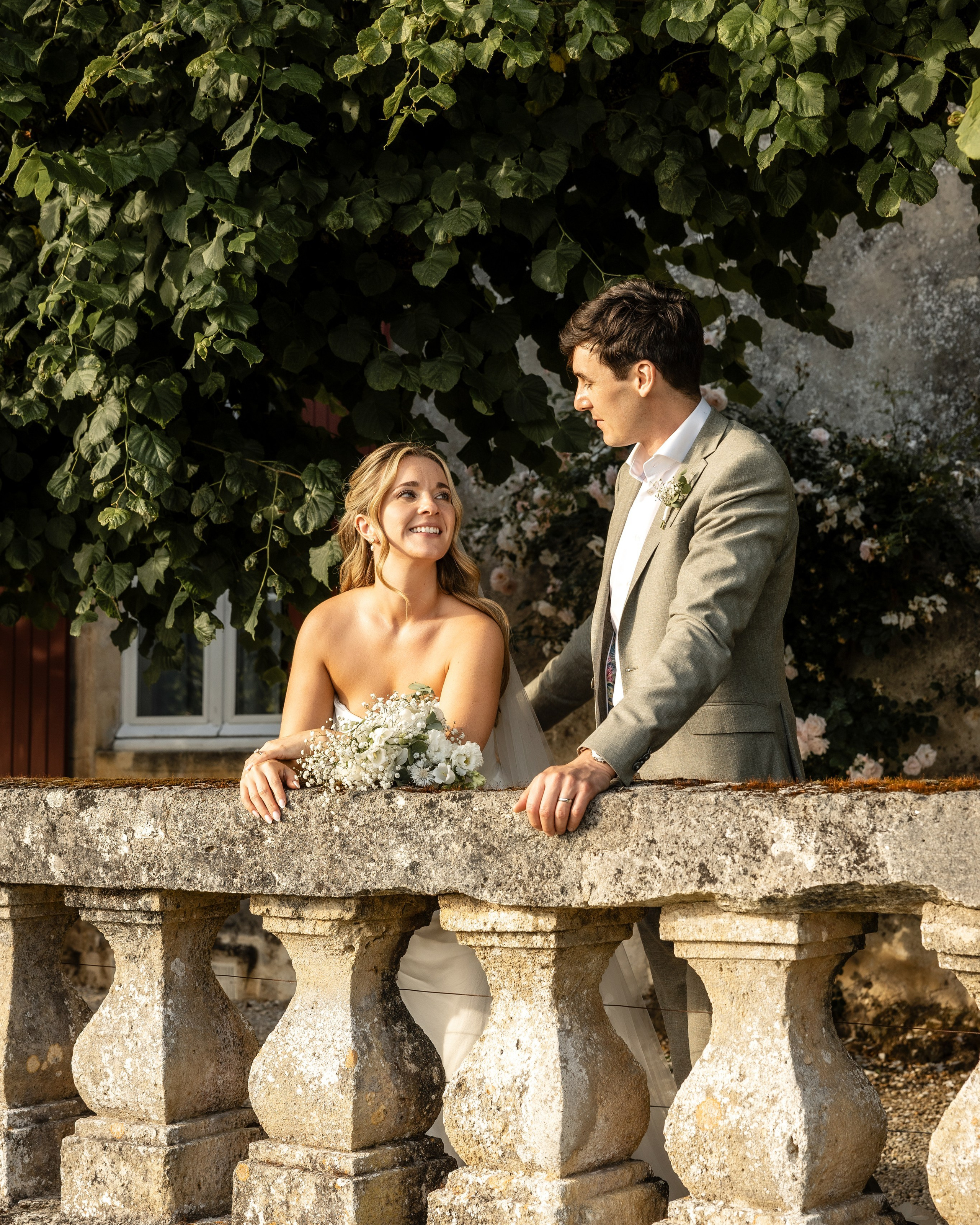 Bride and groom standing together on a historic stone balcony at Château Sentout during their wedding day in France.