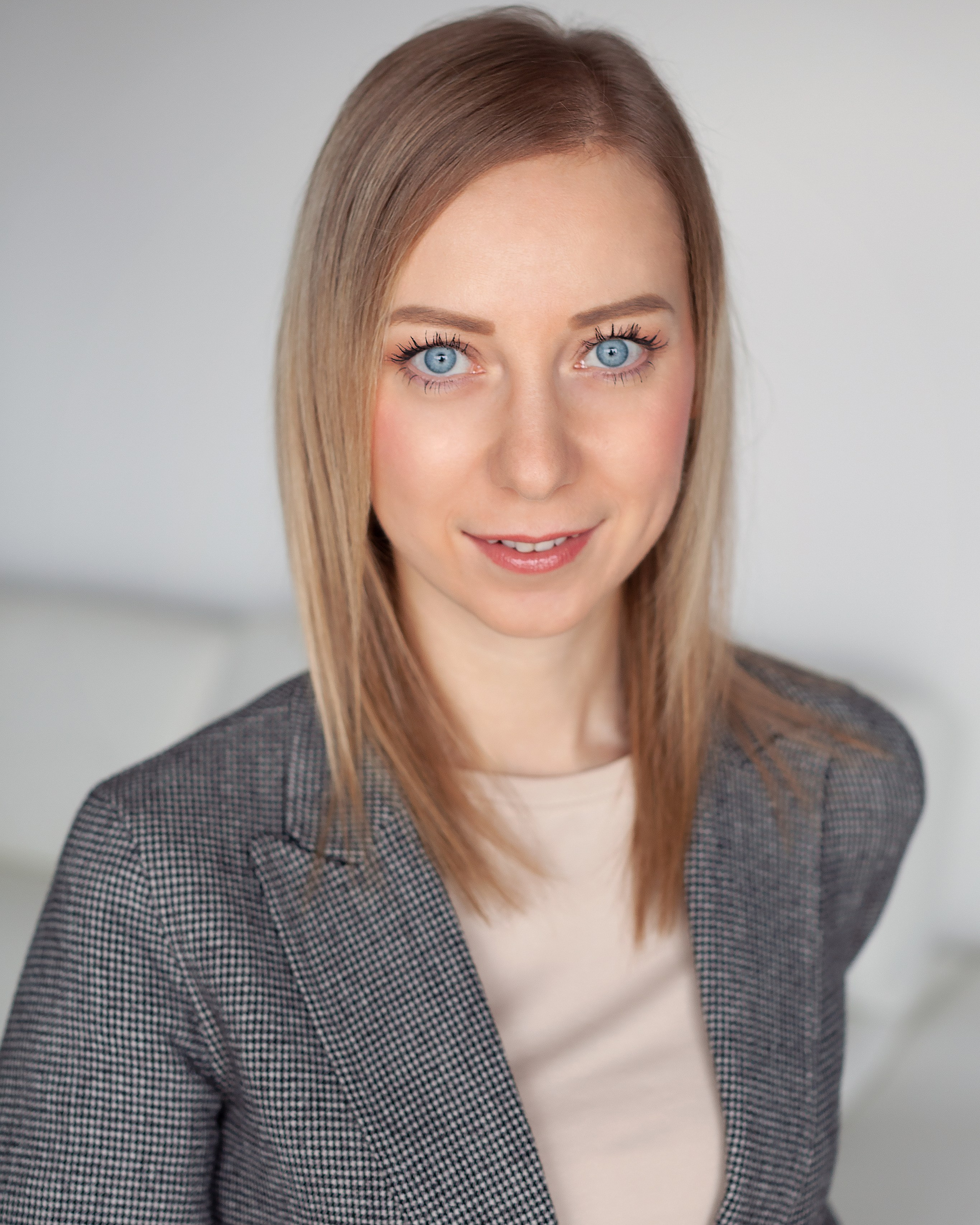 corporate headshot of a woman in a grey blazer during a professional photo session
