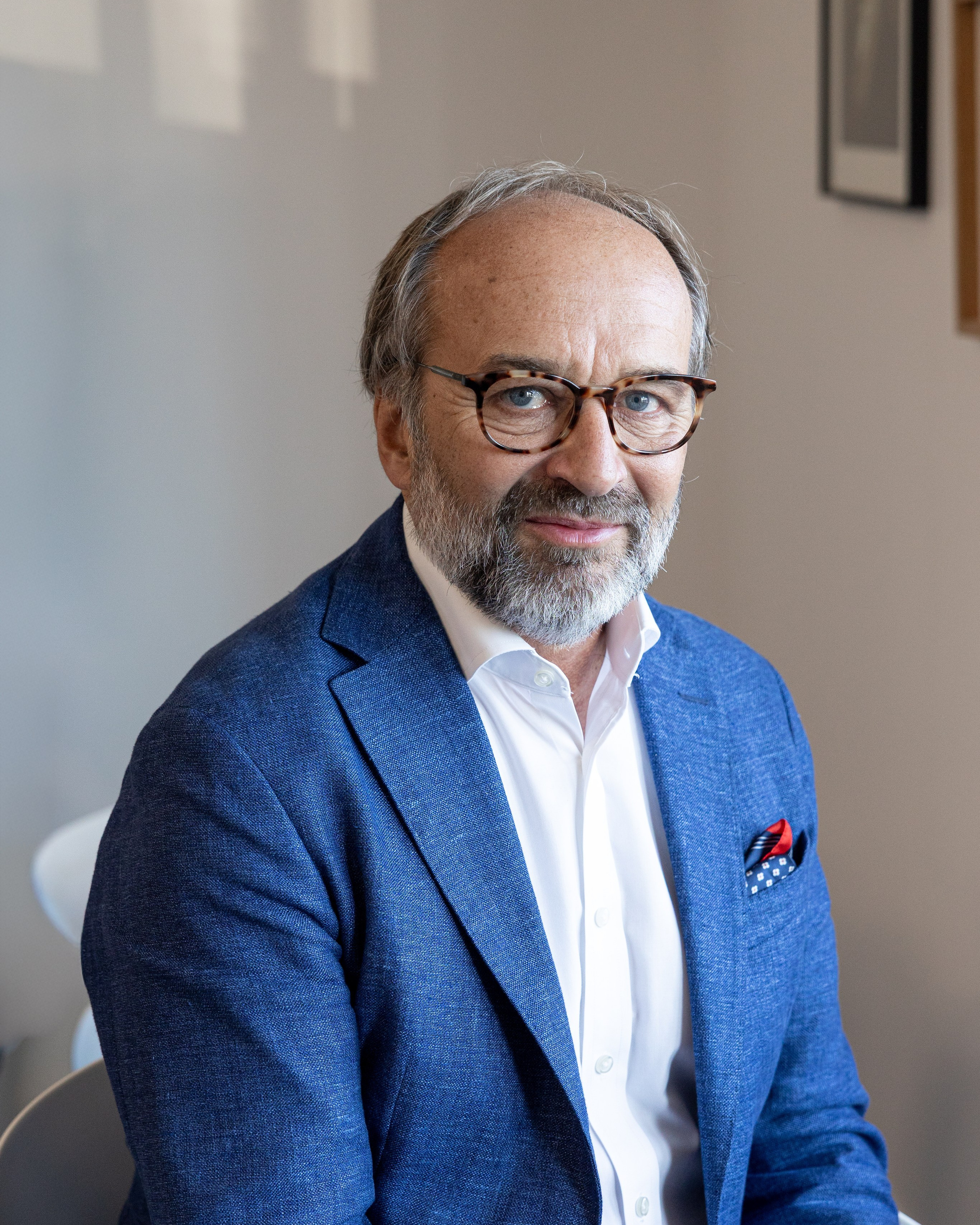 professional portrait of a businessman in a blue jacket sitting indoors during a corporate photo session