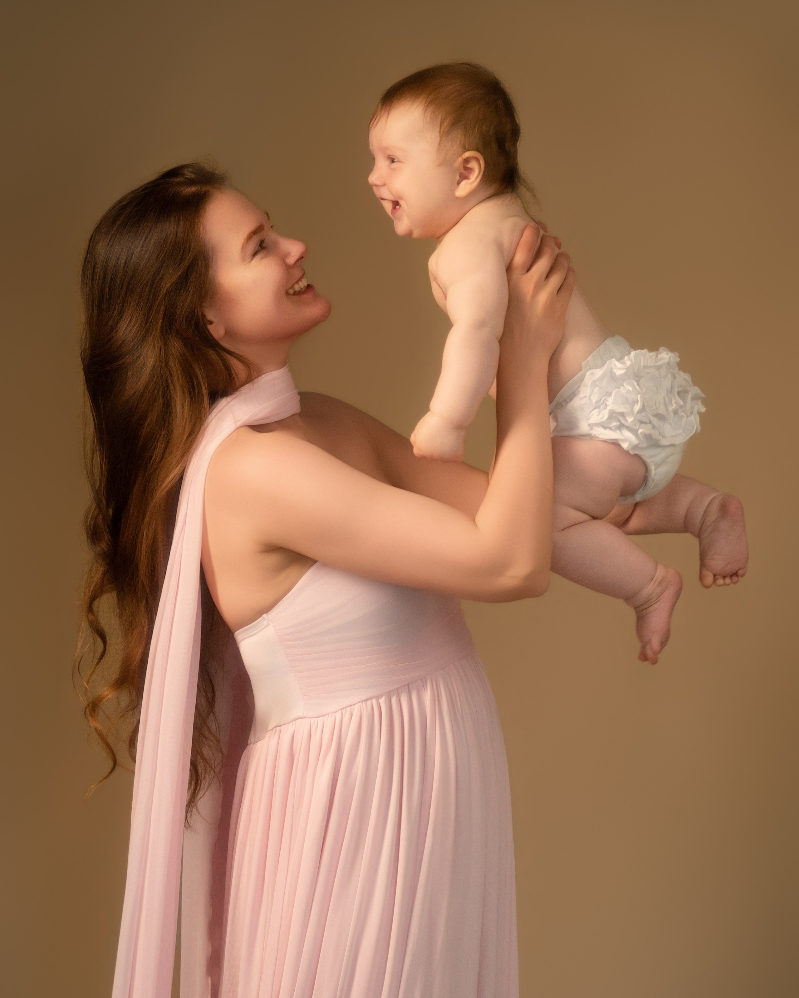 Connecticut motherhood portrait, mother lifting laughing baby up in pink chiffon dress, soft studio light