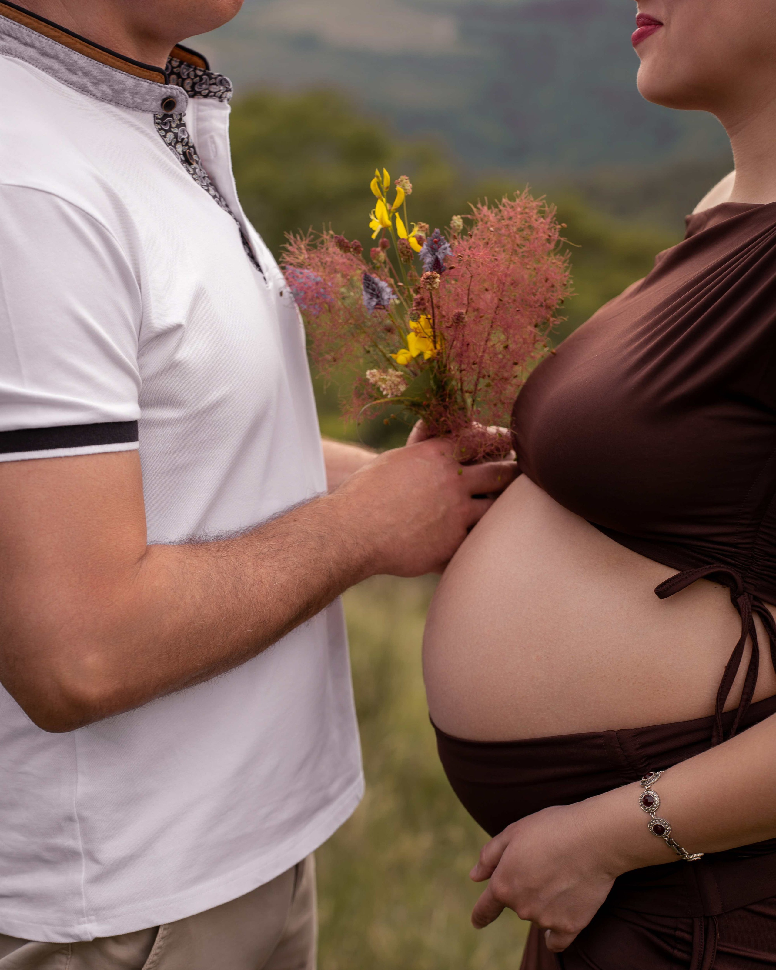 Dettaglio delle mani dei futuri genitori sul pancione durante una sessione maternity