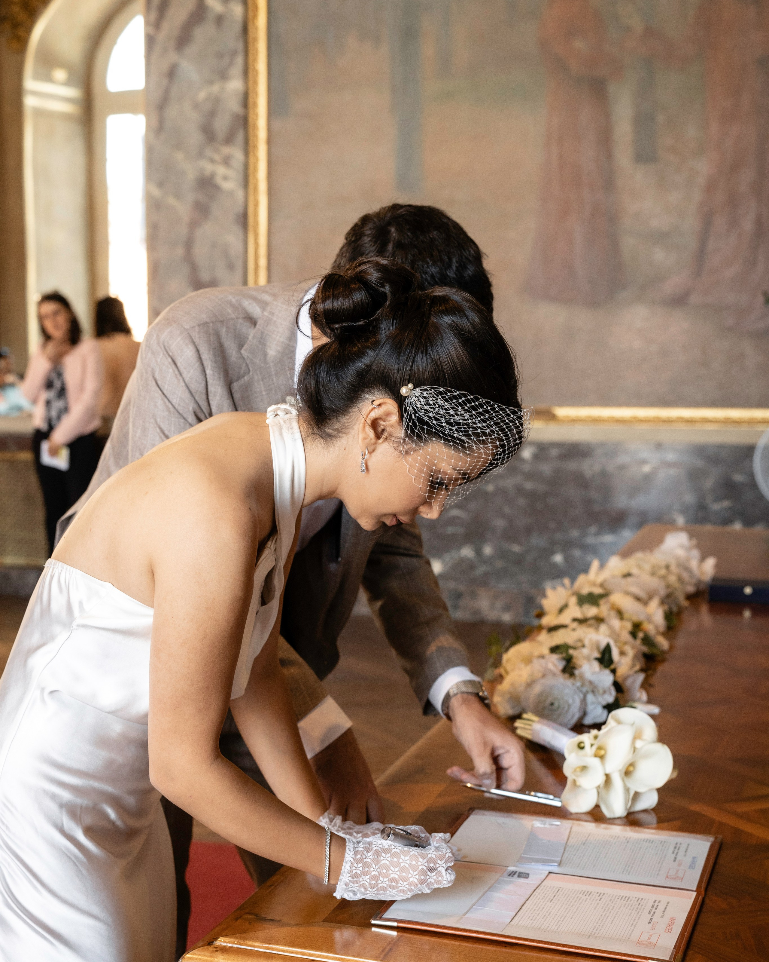 Bride in a white halter gown signing the wedding register with a white calla lily bouquet