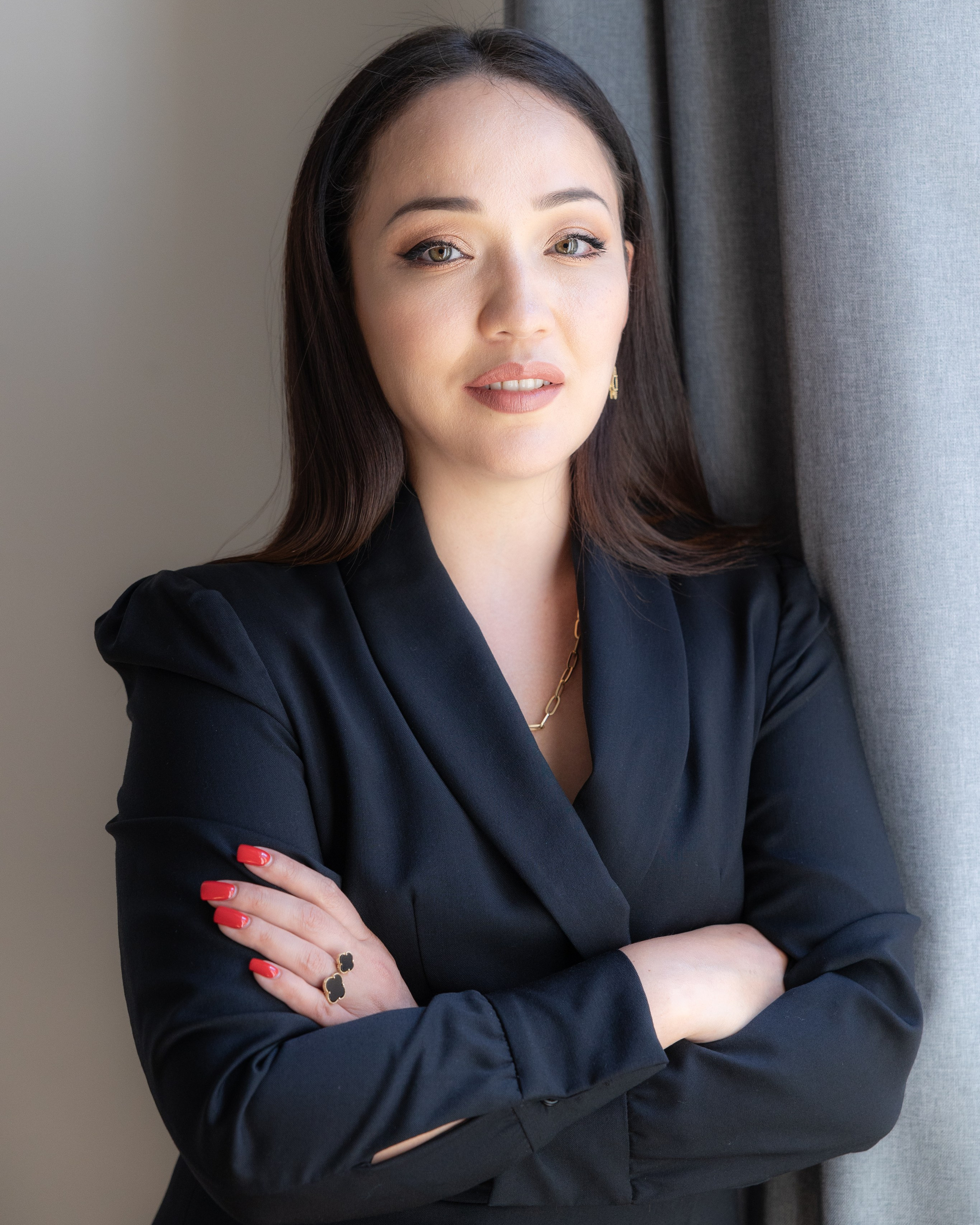 Brunette in black sleeveless top with arms crossed, confident brand portrait, soft daylight