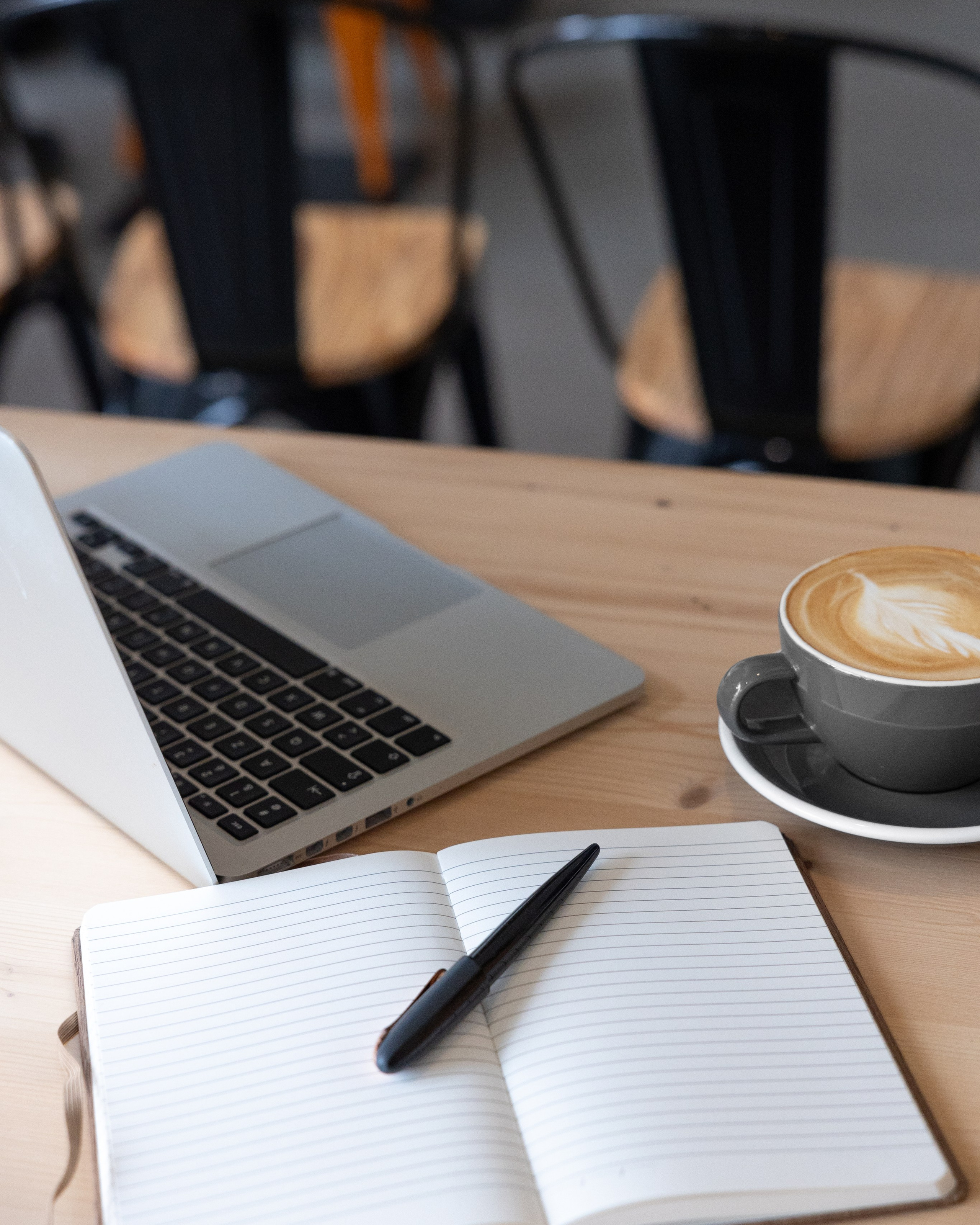 Préparation du brief pour séance corporate à Toulouse, ordinateur portable et carnet ouvert à côté du café sur table en bois de café, planification avant la séance