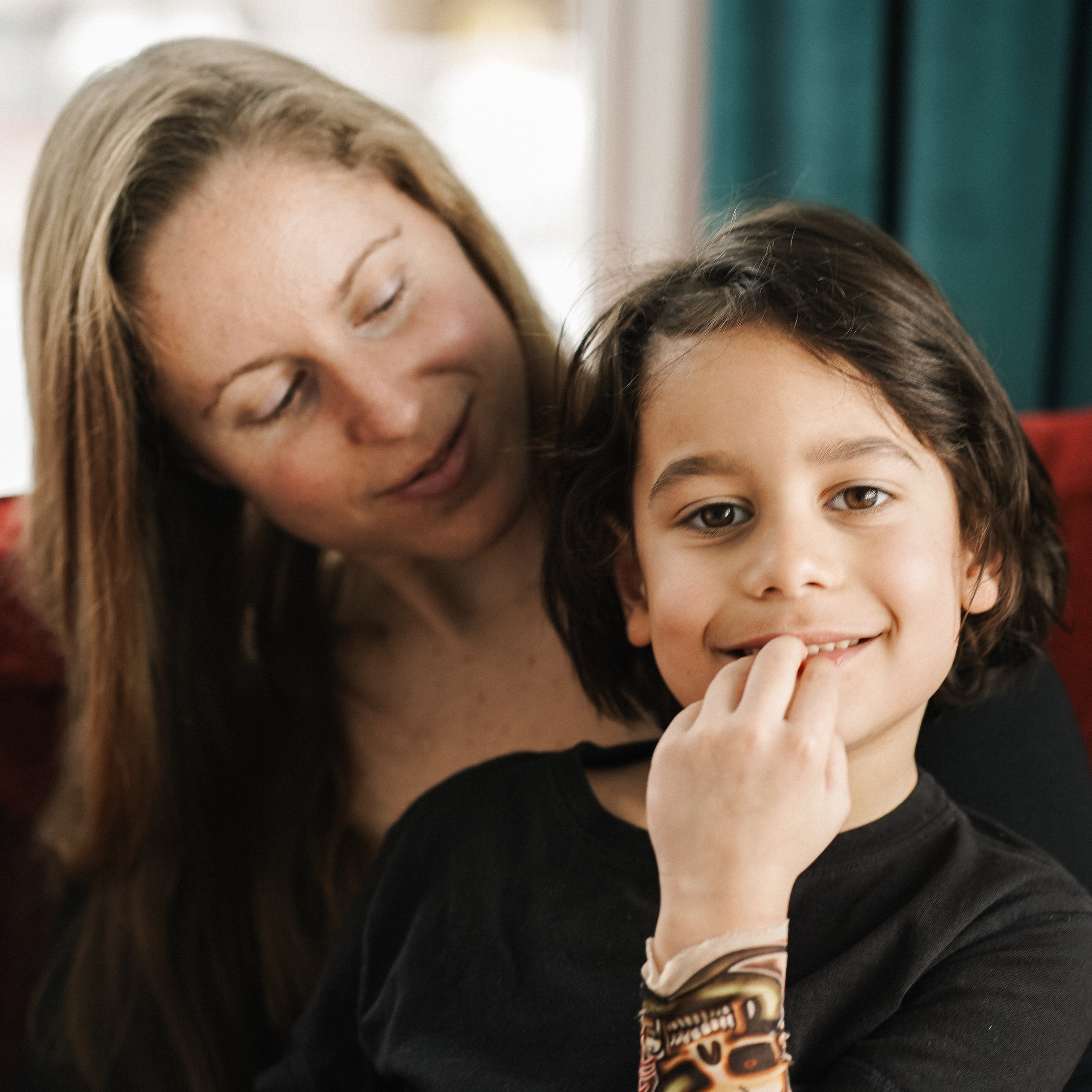 Burnaby home photo session for a mother and her son, sitting on a couch, she is looking lovingly at him, he is looking straight at the camera