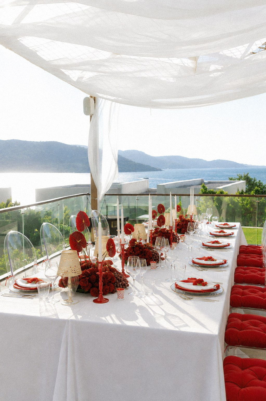 Bodrum wedding design concept with white draping, red flowers and panoramic Aegean Sea views
