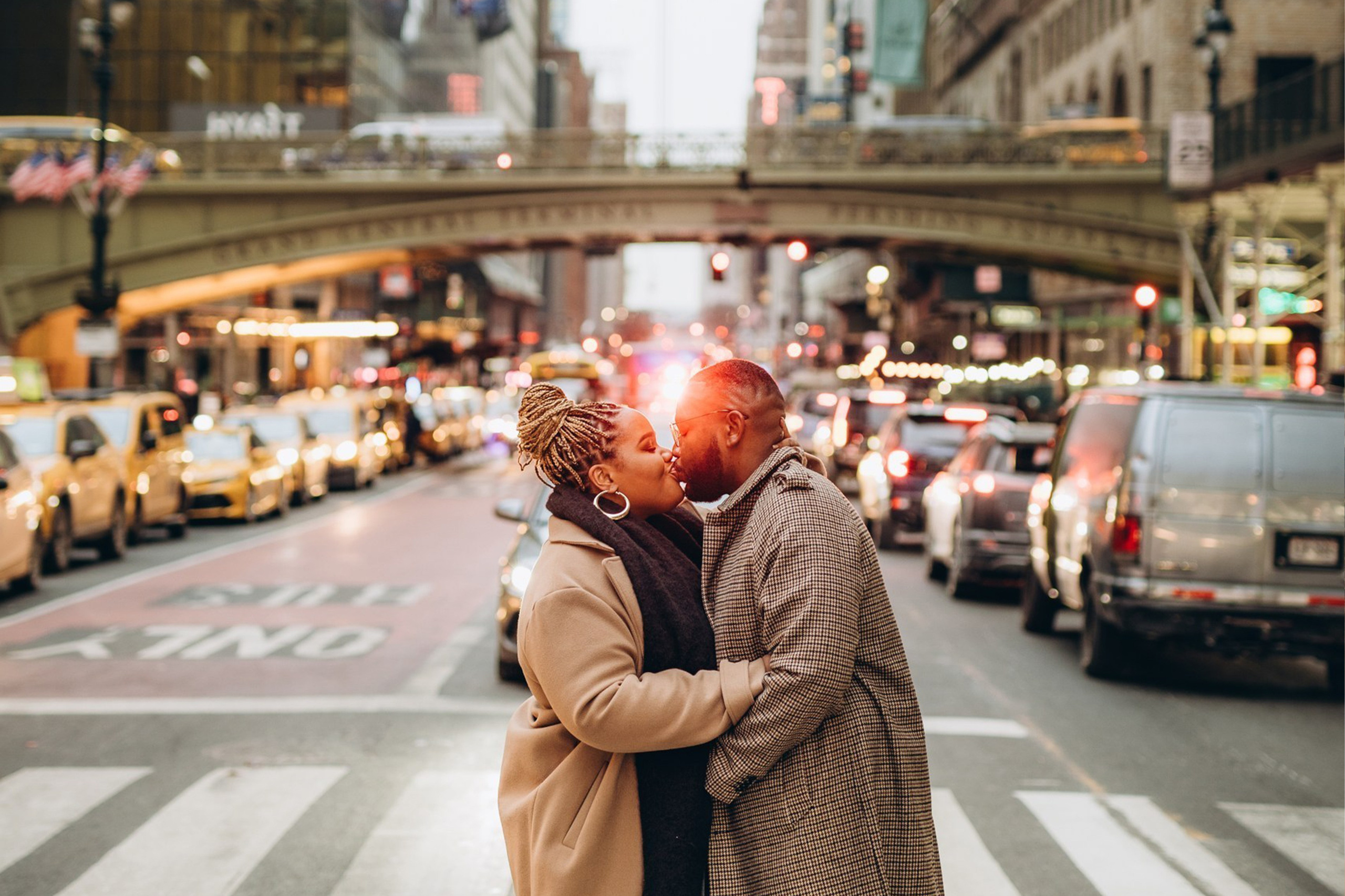 Couple kissing in Manhattan across a New York City street with a yellow taxi in the background — lifestyle engagement photo with cinematic vibe
