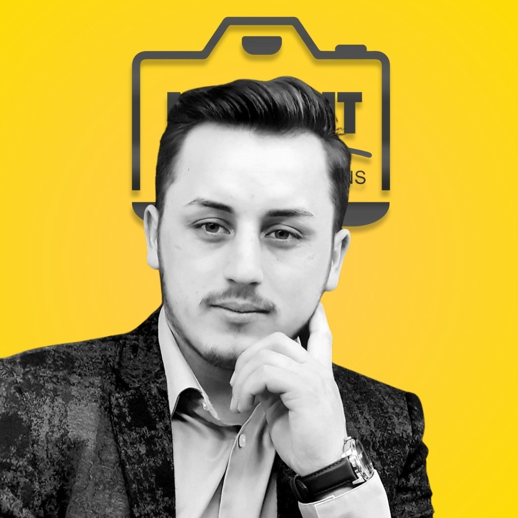 Portret profesional al unui bărbat pe fundal galben cu logo, expresie zâmbitoare