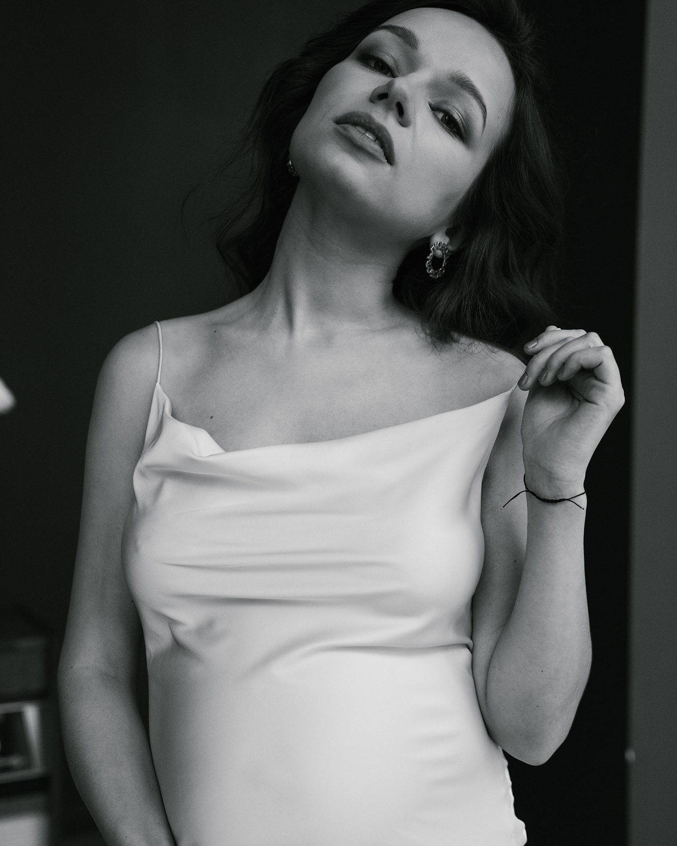 Pregnant woman is posing like on fashion magazine holding holding strap of her dress