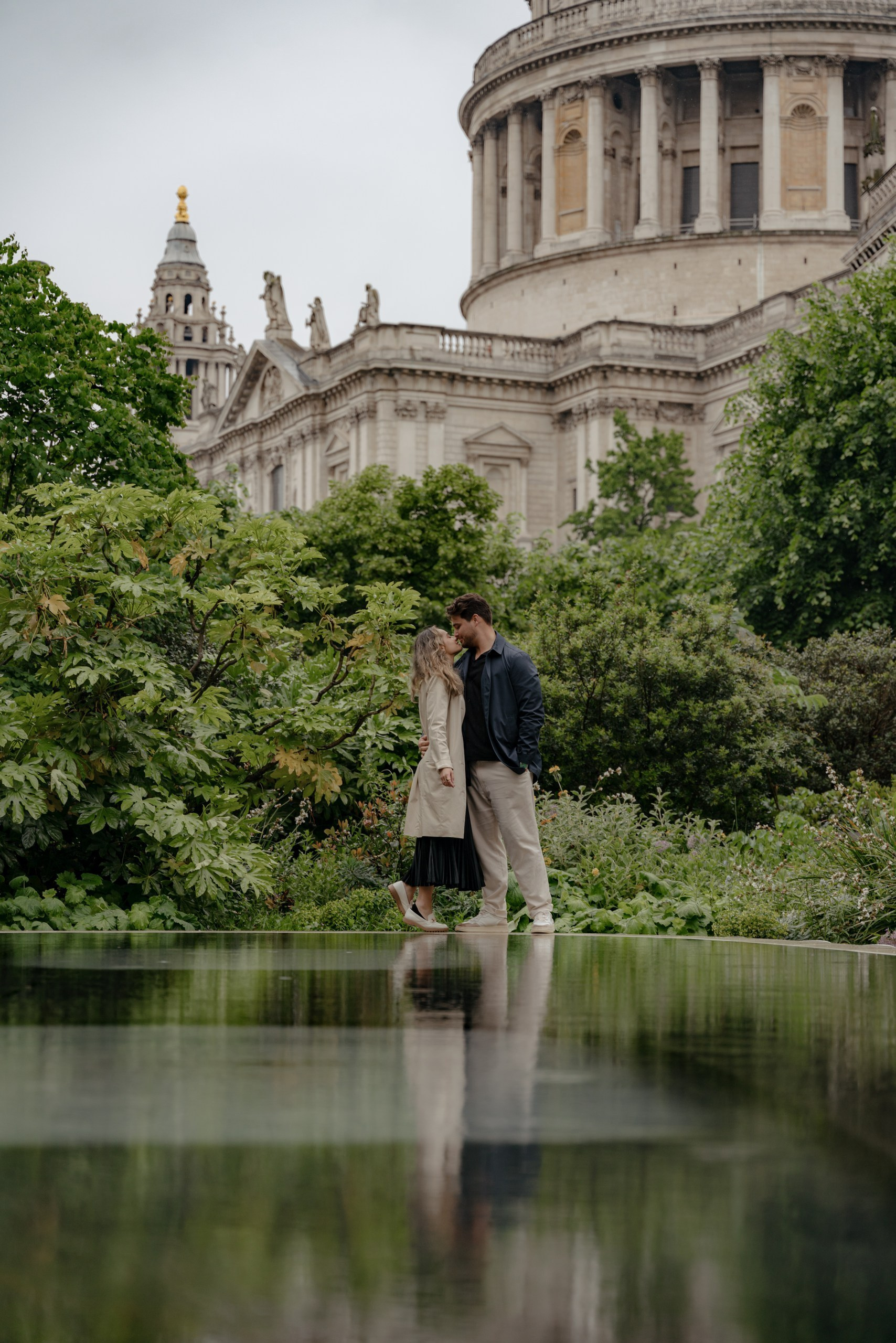 Couple kissing near St Paul’s Cathedral during London engagement photoshoot in soft rain.