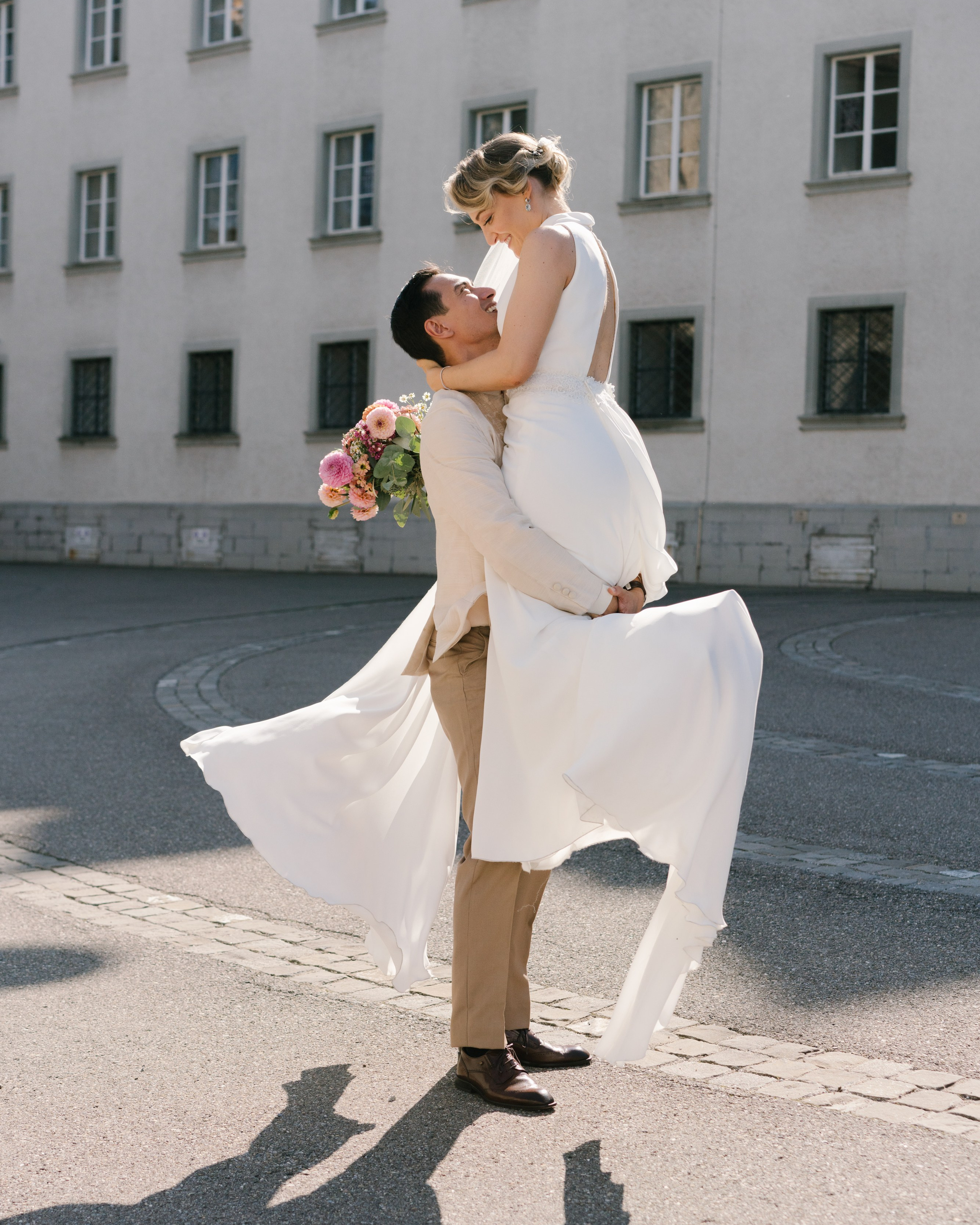 Mann hält seine Braut und dreht sie in natürlicher Pose in der Nähe der Kathedrale von St. Gallen in der Schweiz während der Hochzeitsfotosession um