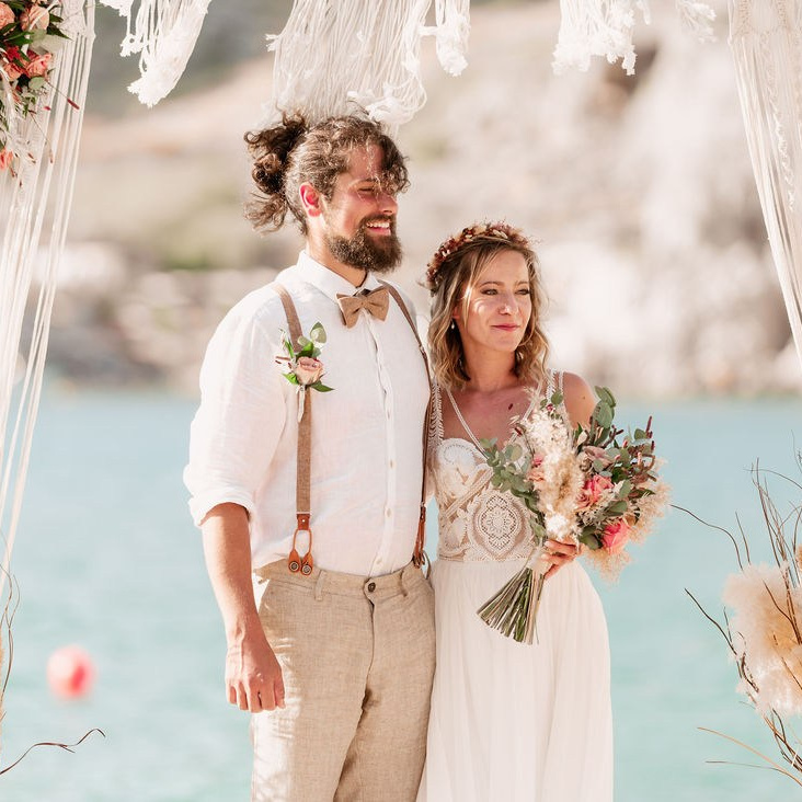 Wedding on Rhodes: Bride and groom at the beach of Lindos St. Paul’s Bay, summer wedding photoshoot in Greece.