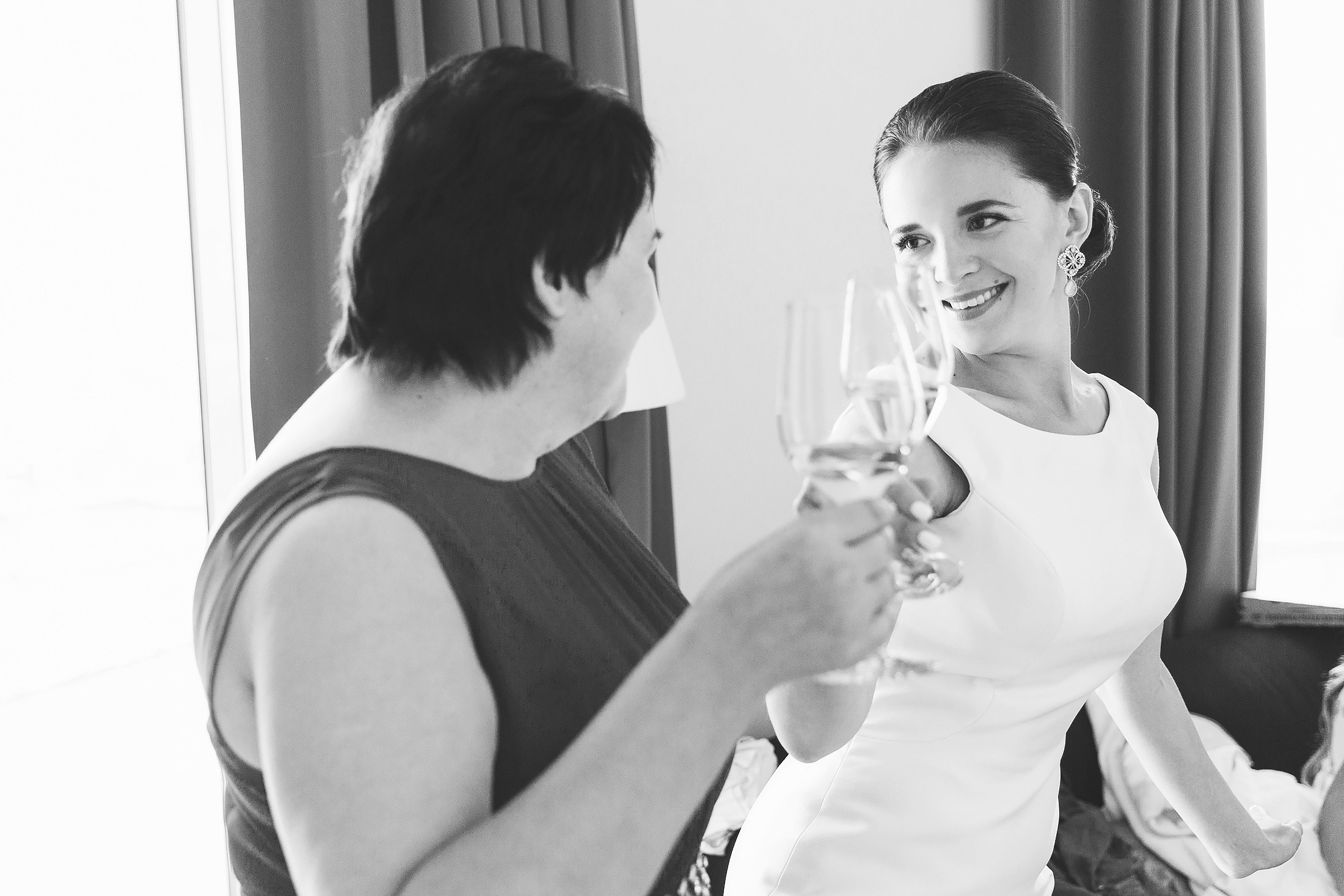 Bride clinking champagne glasses with her mother during wedding morning preparations