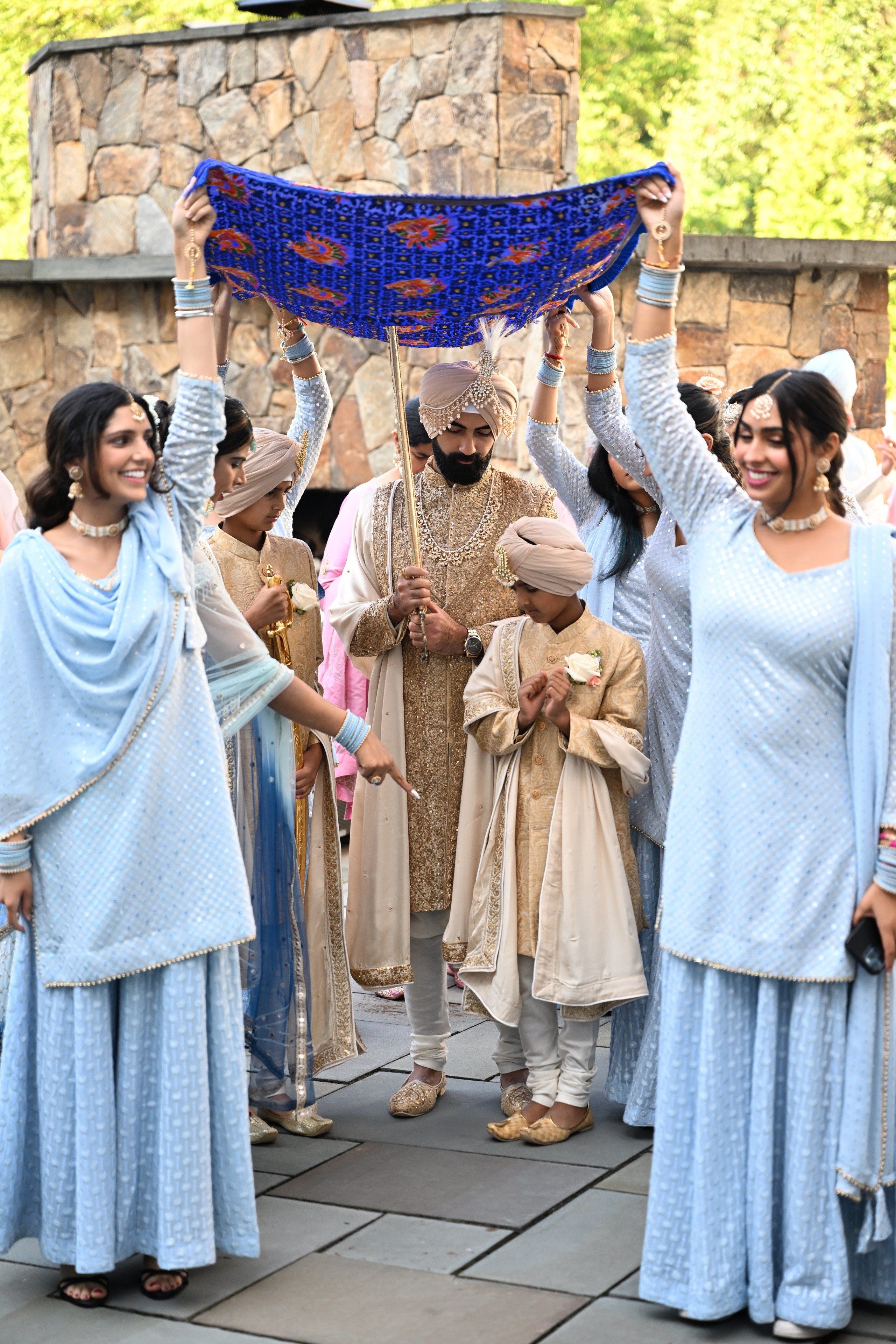 a group of people standing around a man holding a blue umbrella