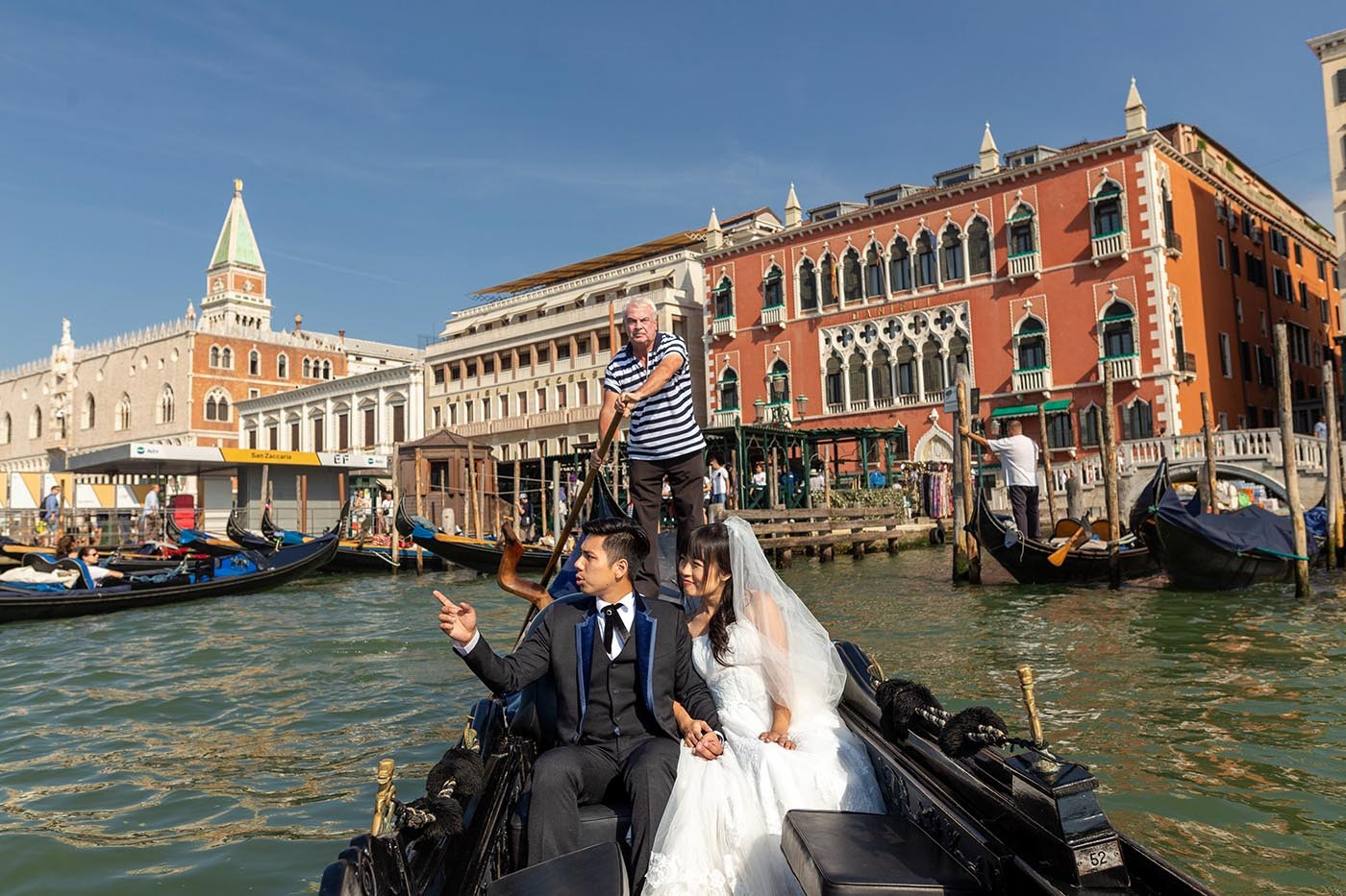 Newlyweds are steered into the lagoon by a gondoler during their early morning tour of the canals of Venice  - Kurt Vinion Photography