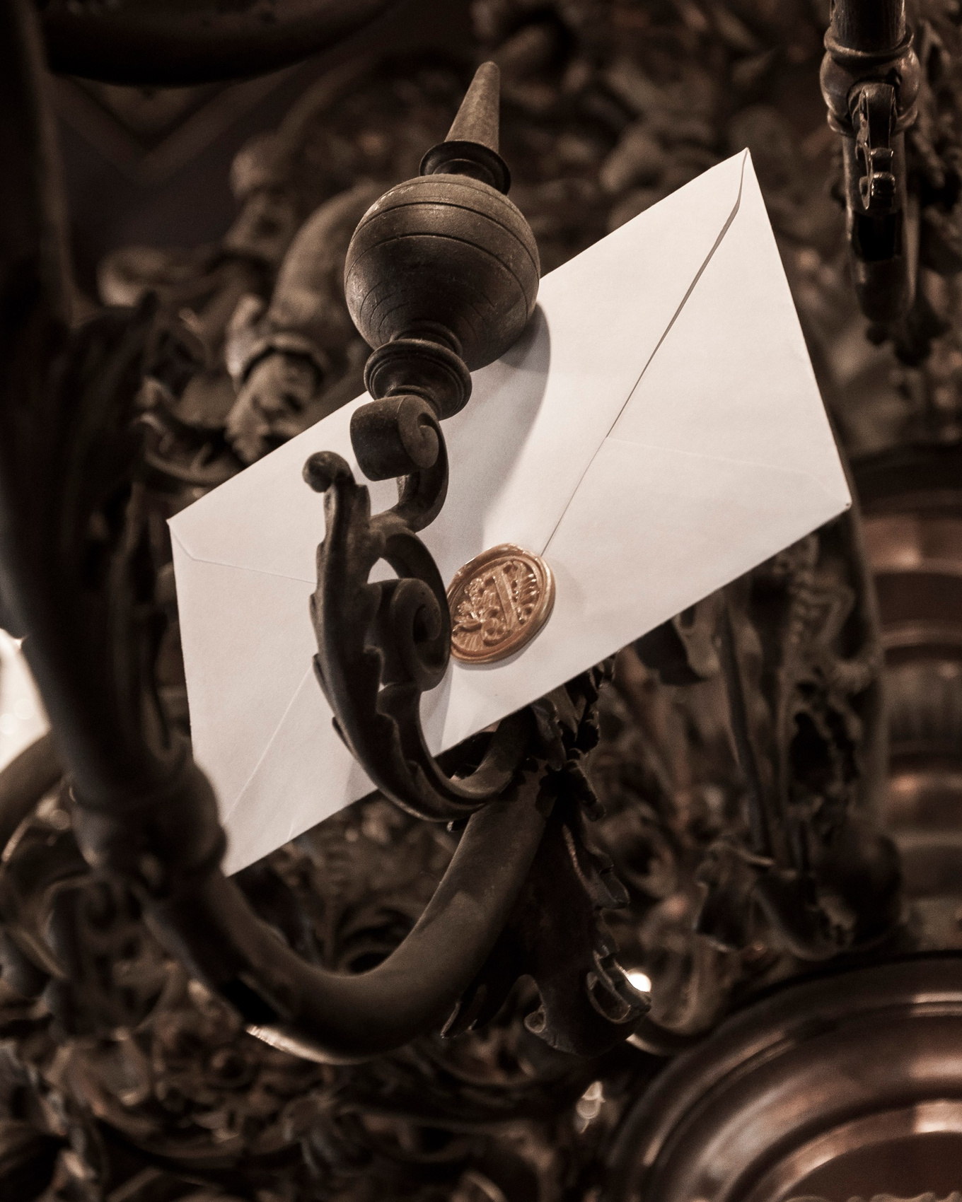 A luxurious envelope featuring an elegant golden seal, sitting in a bronze chandelier, designed to enhance branding and marketing efforts, symbolizing sophistication and exclusivity.