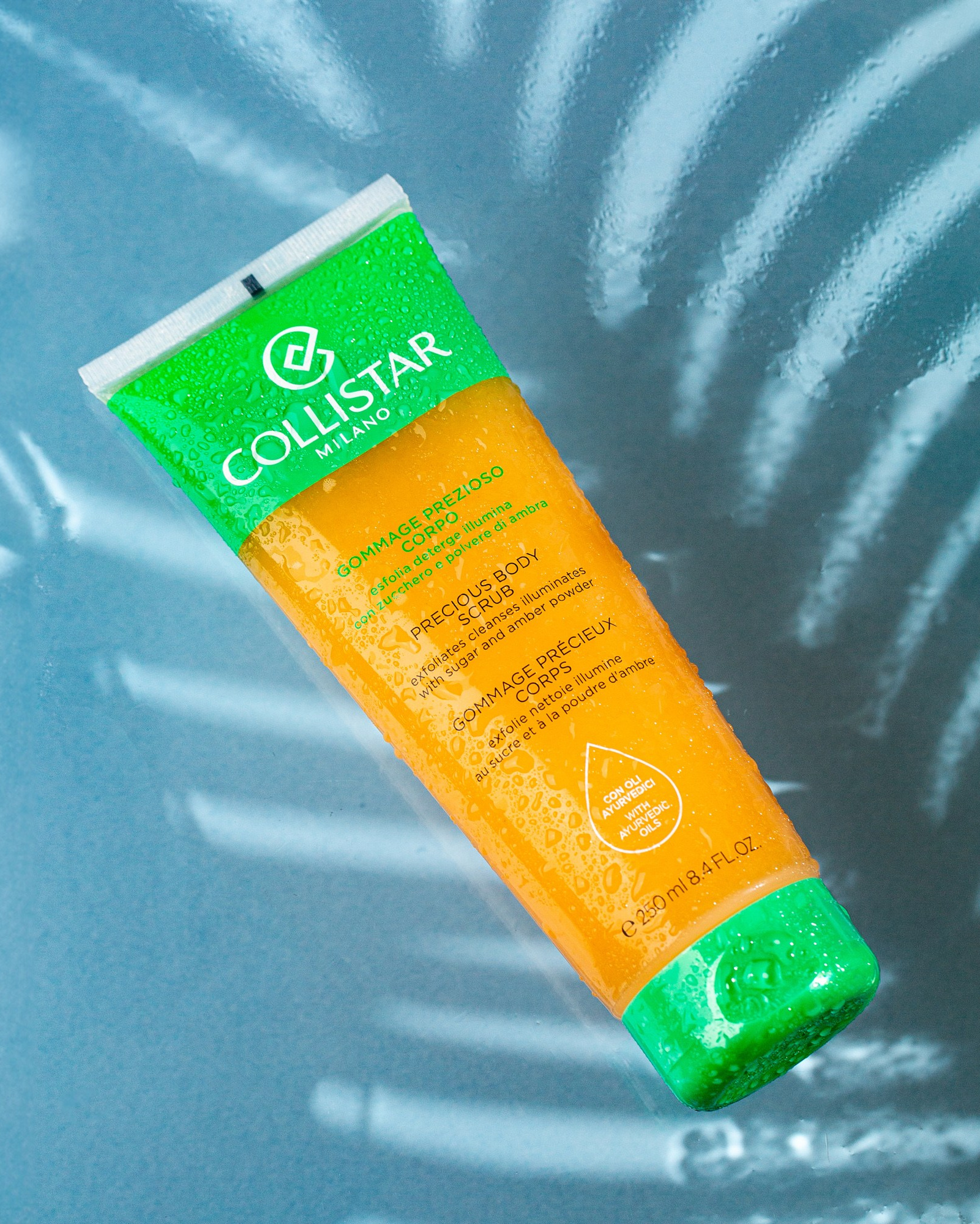 Parlaq yaşıl rəngdə qapağı və ucu olan, narıncı rəngli dənəcikli Collistar Precious Body Scrub borusu. Məhsulun üzərindəki yazılardan "Gommage Prezioso Corpo" və "Precious Body Scrub" hissələri oxunur.