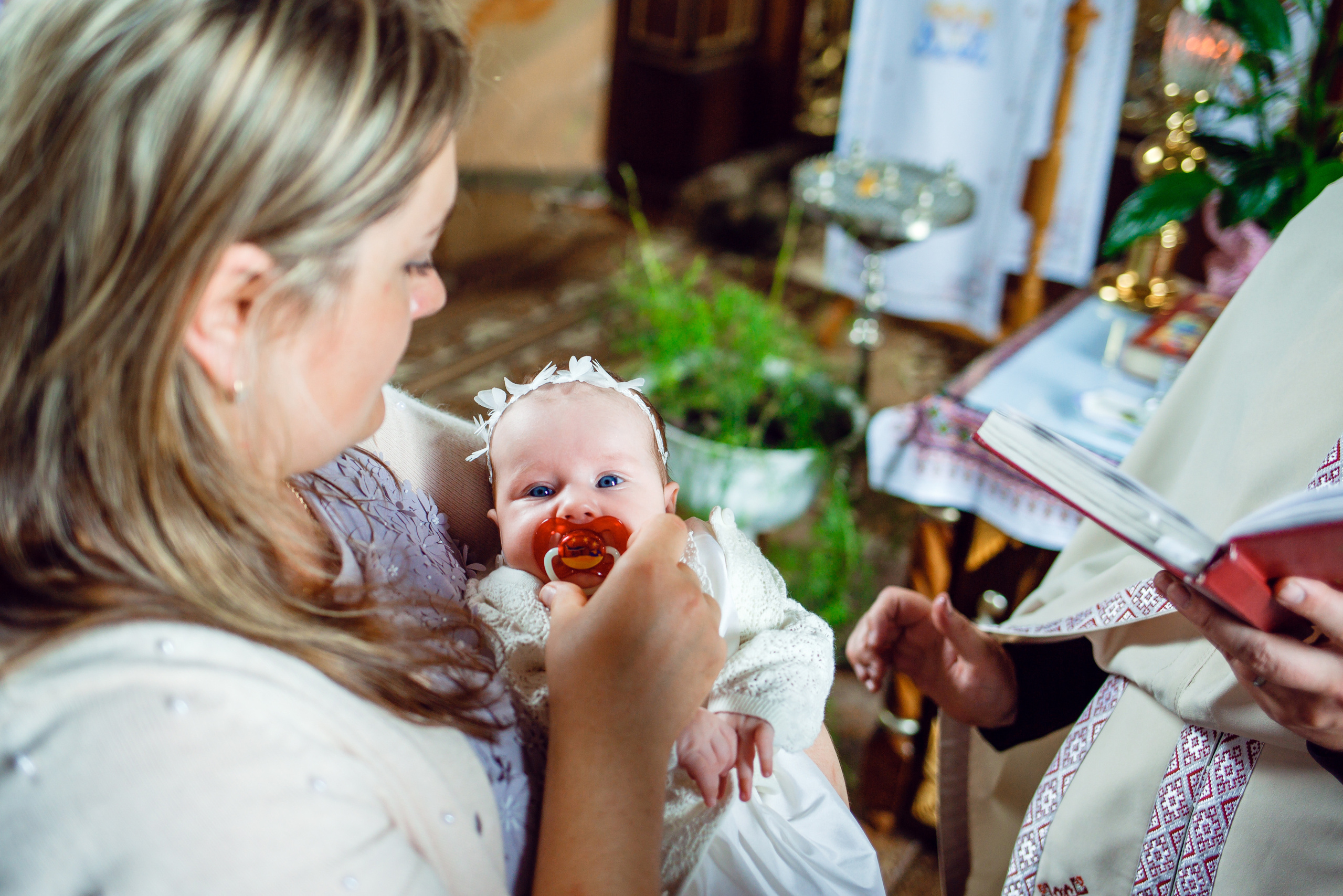 Дитина на руках в хресної мами під час Хрещення в церкві