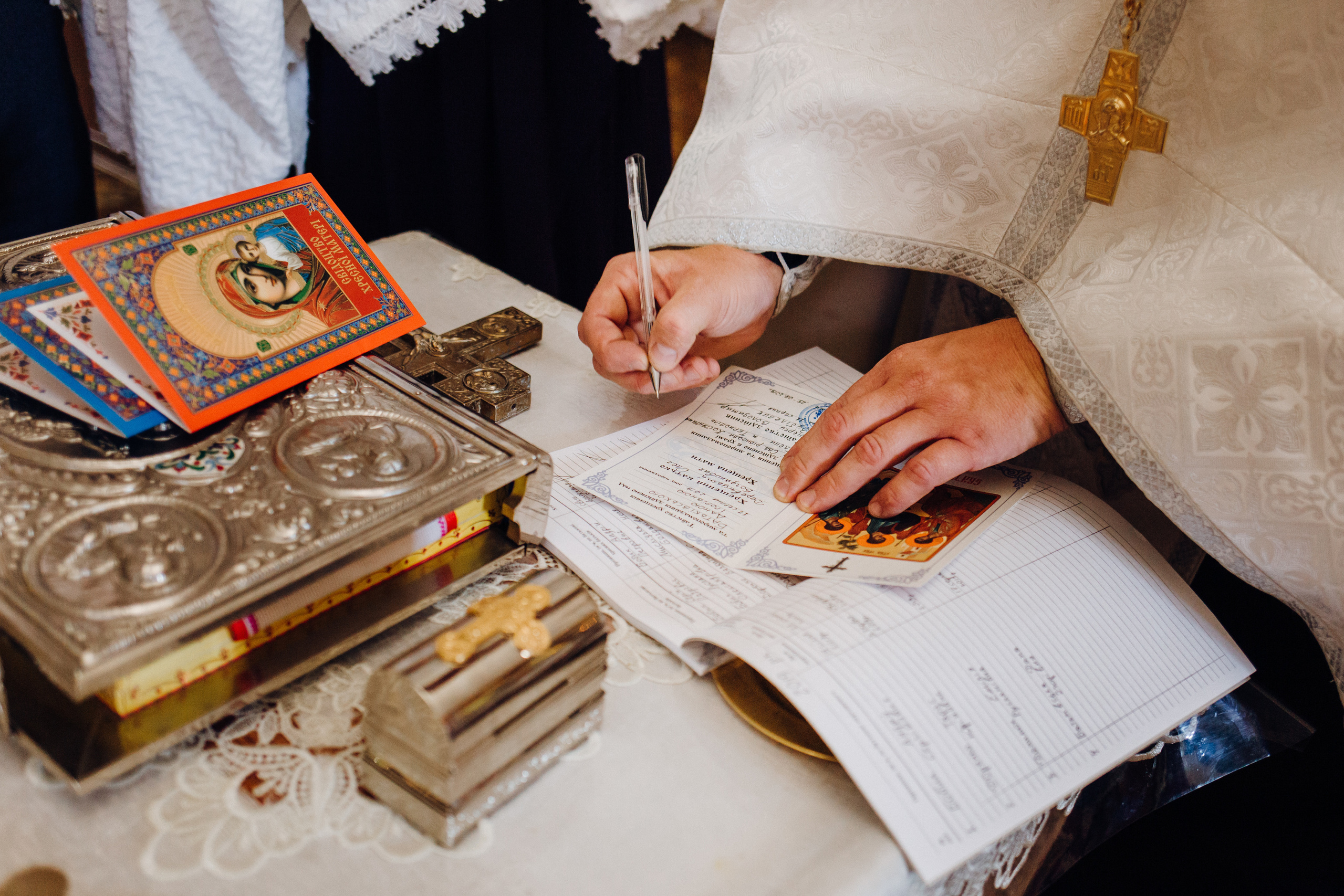 Священник підписує свідоцтво про Хрещення