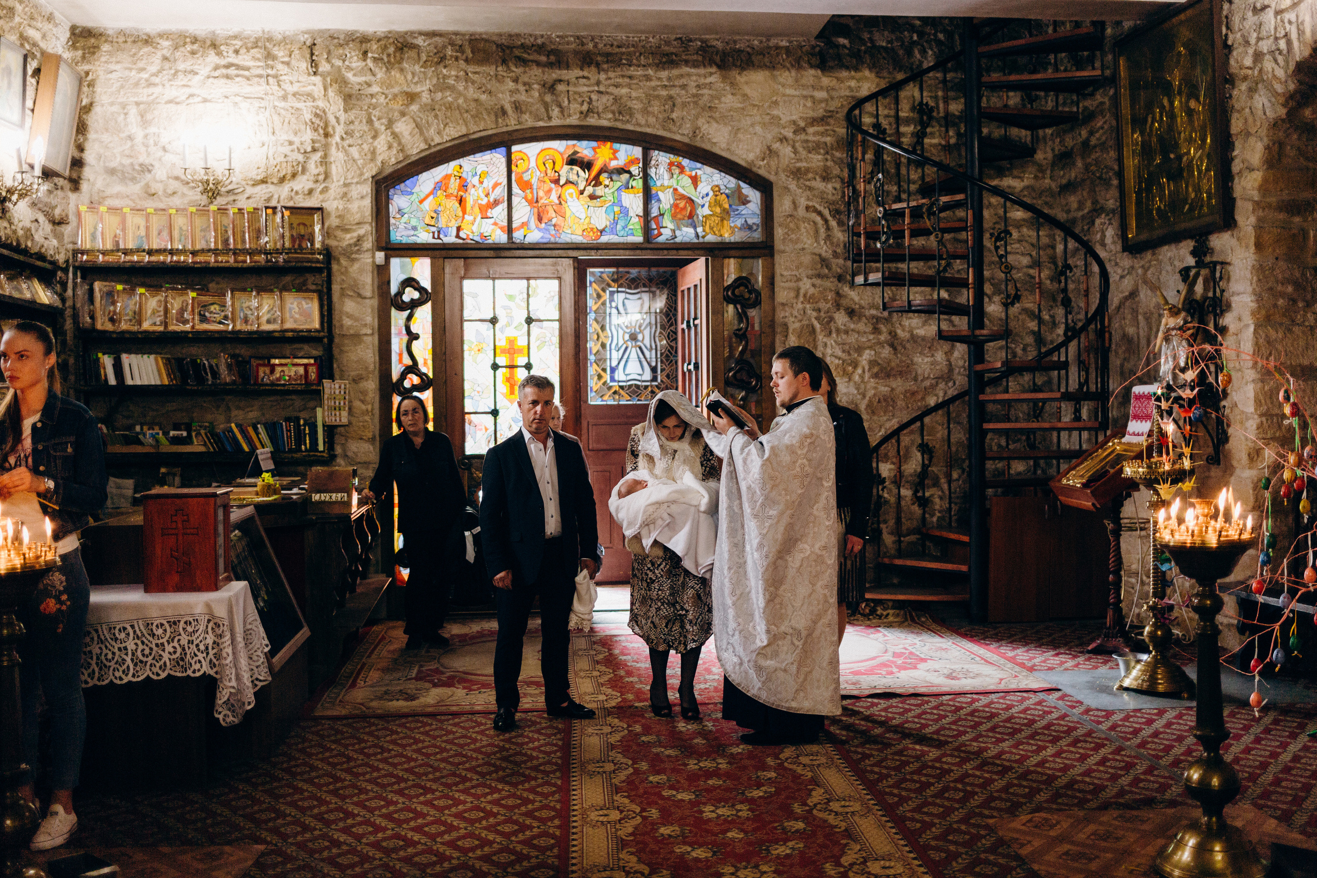 Священник читає молитву над мамою дитини під час хрещення