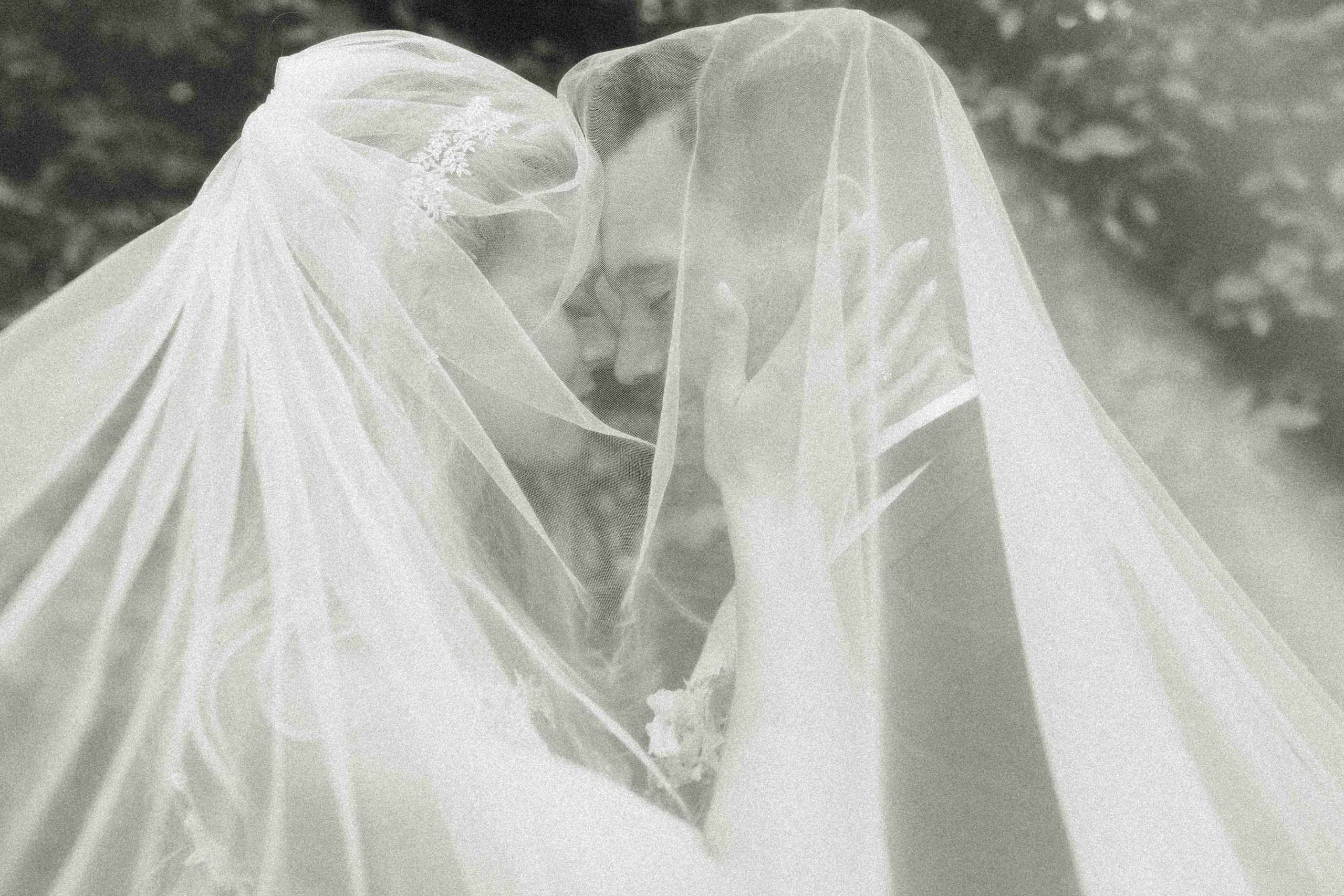 Schwarzweiss Foto von einem Hochzeitspaar beim Pärchenshooting unter dem Schleier während ihrer Hochzeit in Hannover bei einer Hochzeitsreportage