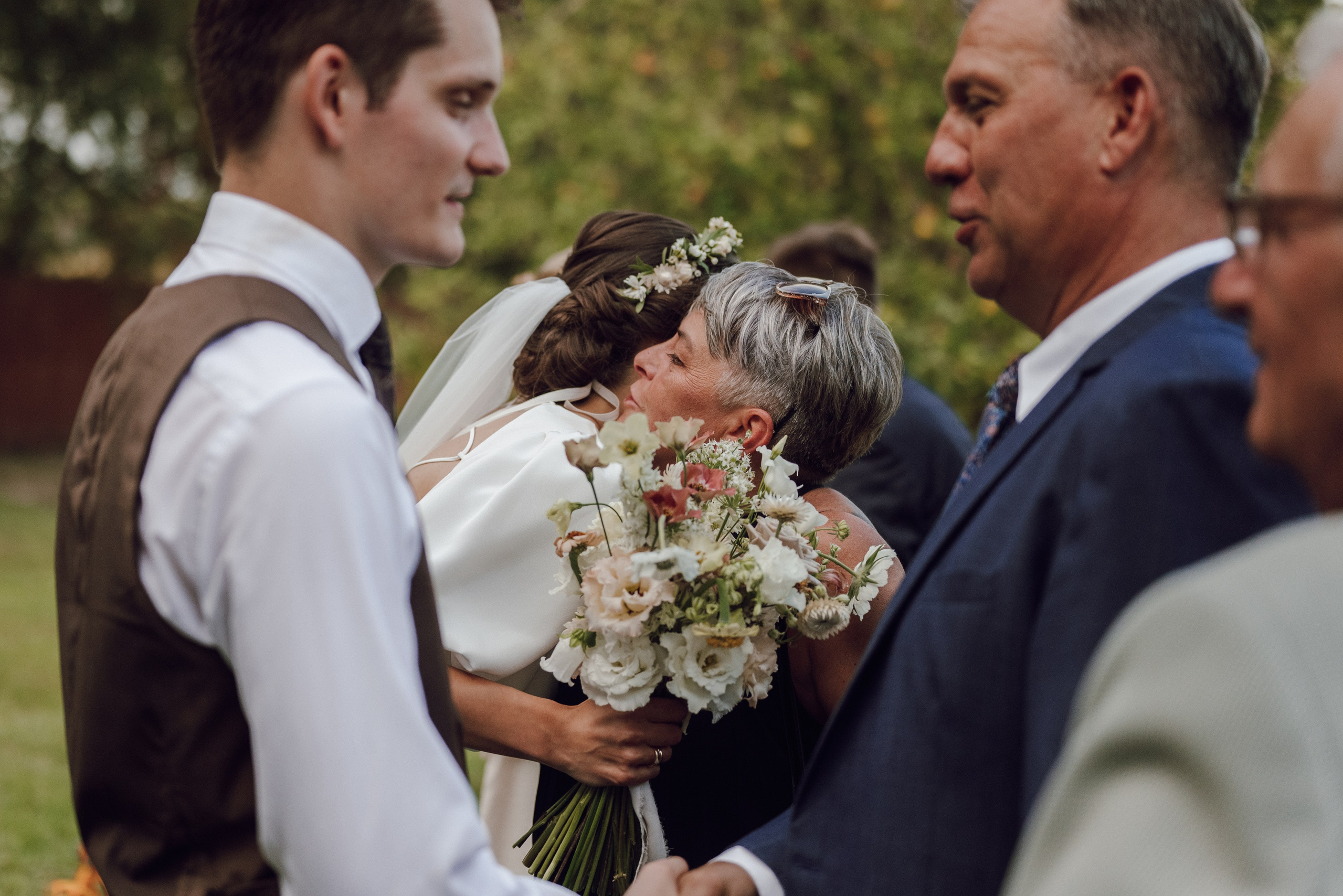 Ojciec wręczający bukiet panu młodemu – wzruszające momenty podczas ślubu, fotografia ślubna Poznań.
