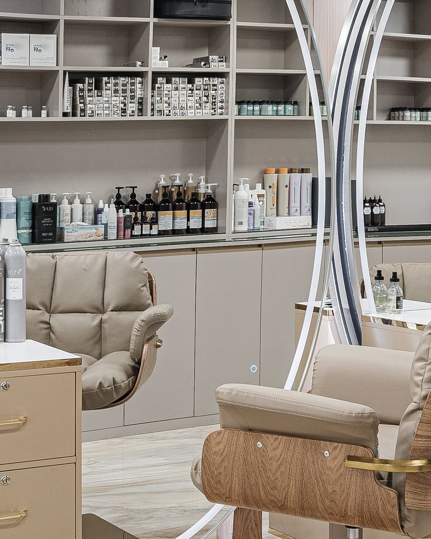 Photographie d’un intérieur de salon de beauté avec fauteuils beiges et grands miroirs.