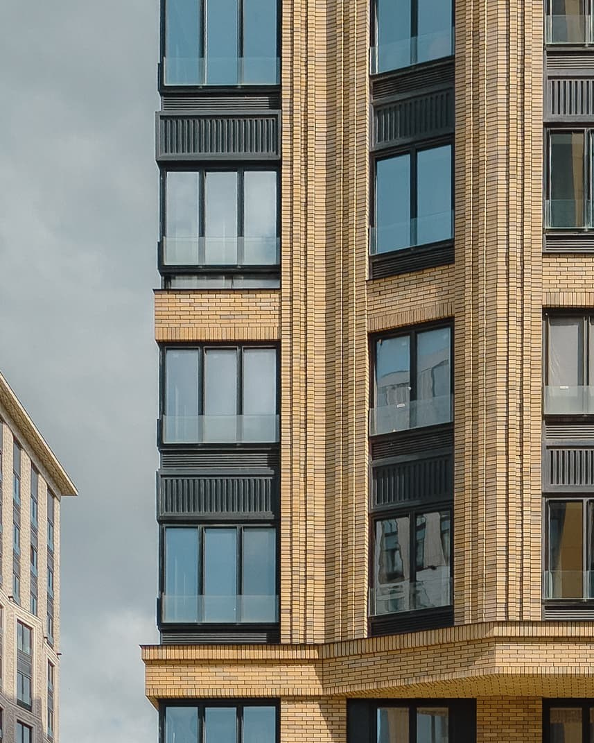 Photographie d’un immeuble résidentiel moderne avec façade en briques jaunes.