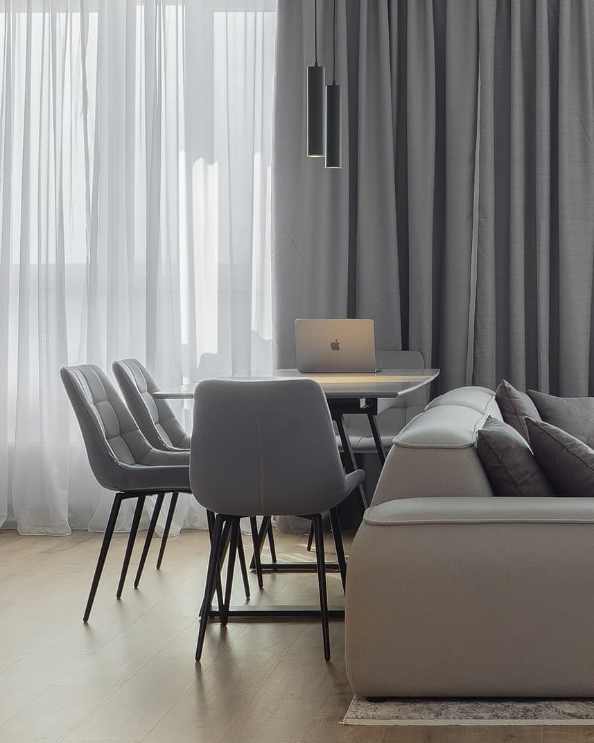 Photographie d’un intérieur moderne — salon et salle à manger avec rideaux gris.