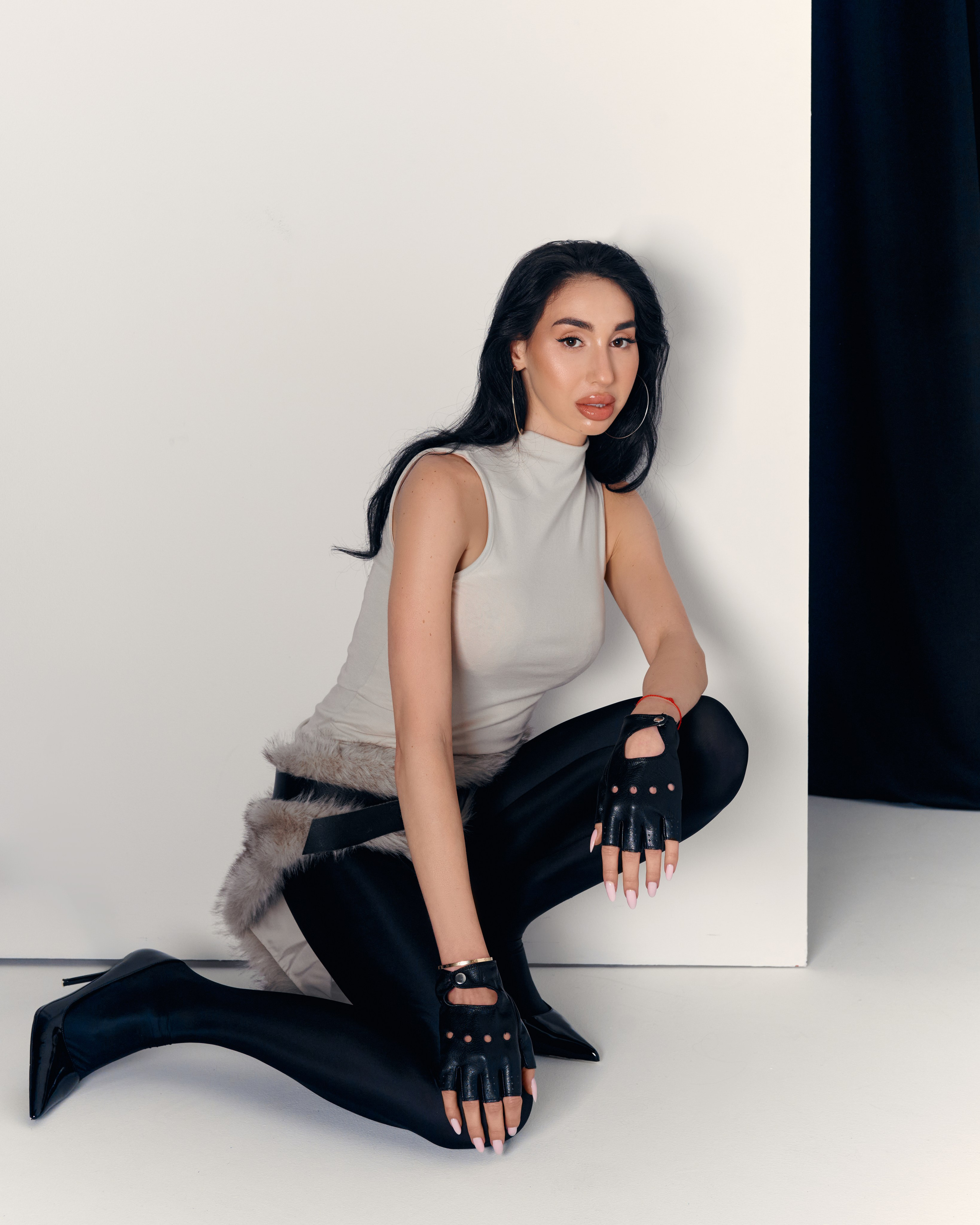 Minimalist studio portrait of Ester Rogovaya styled with a fur skirt, soft light and contemporary mood
