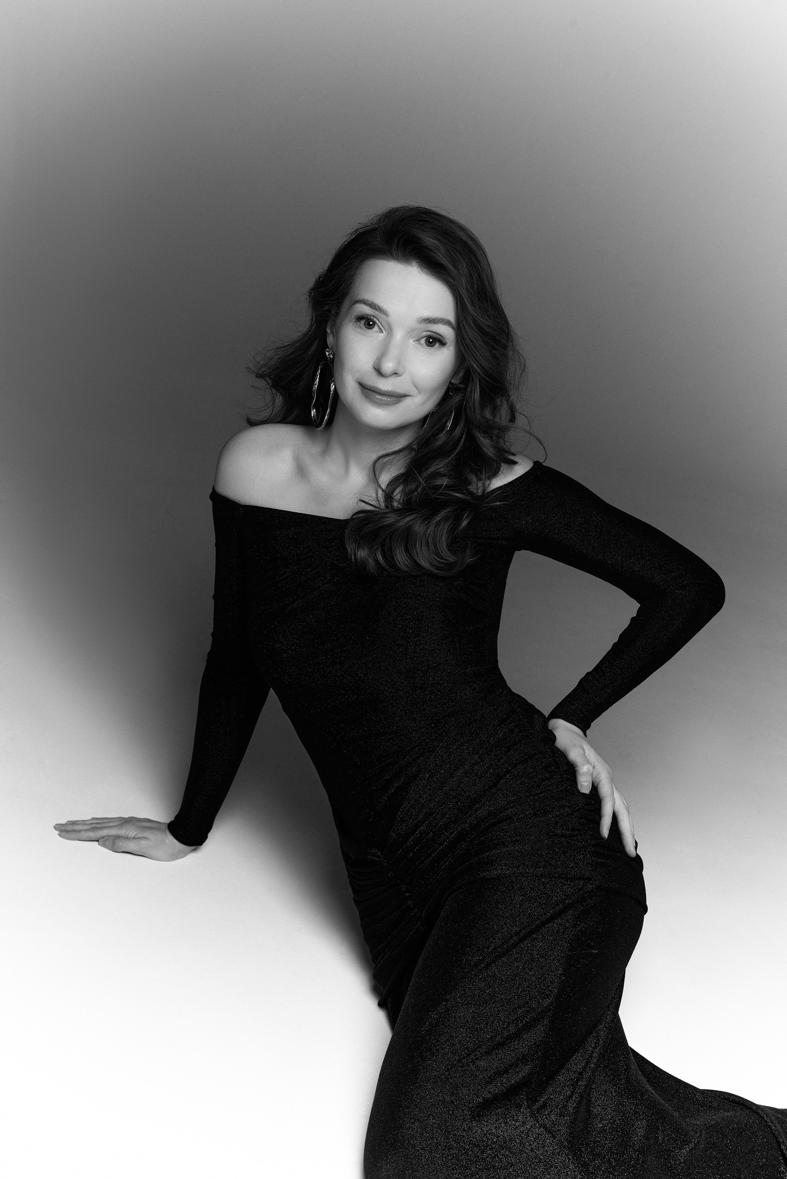 Ekskluzywna fotografia czarno-biała – kobieta w czarnej sukni w dynamicznej pozie, gra światła i cienia
