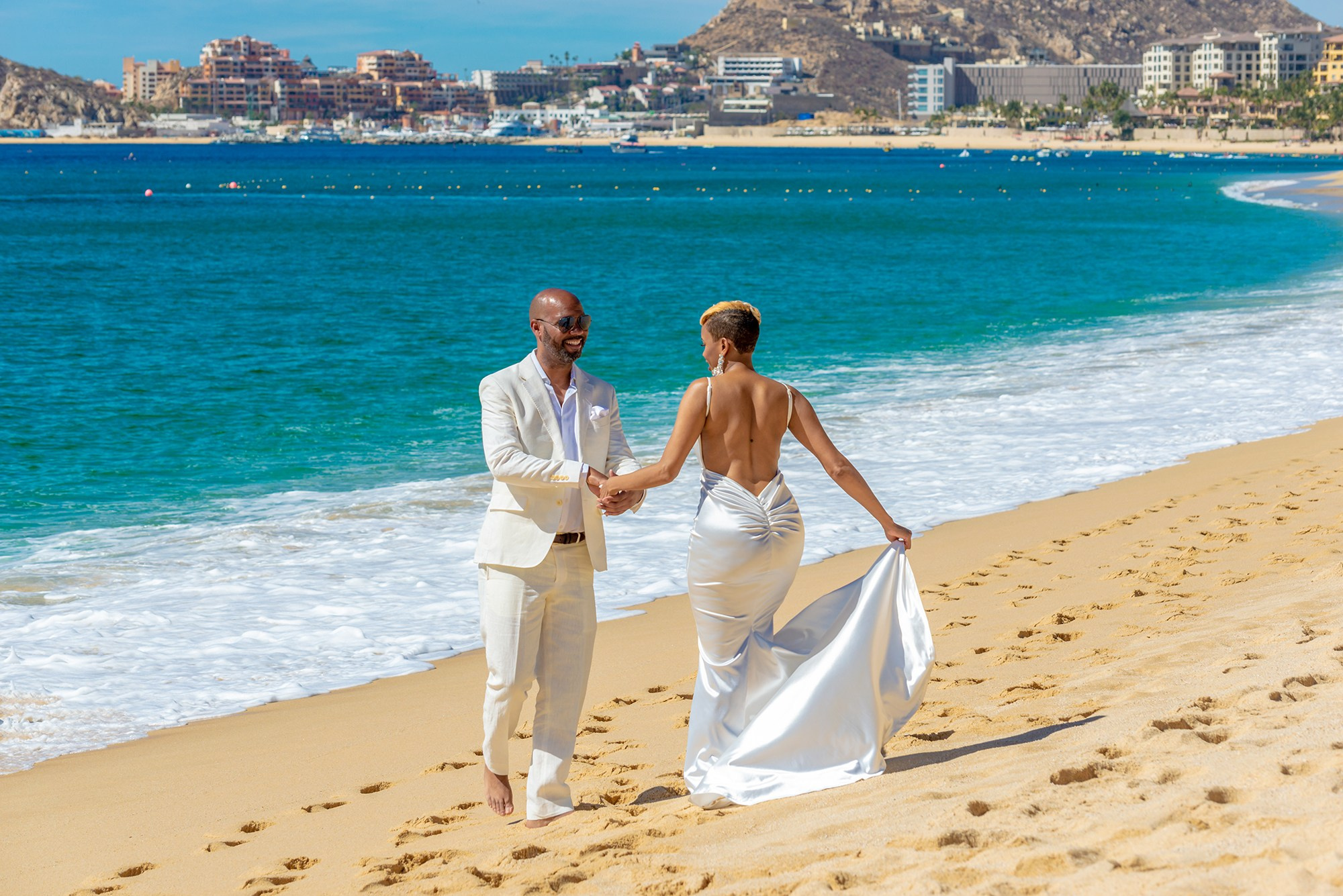Candid wedding portrait in Cabo San Lucas – smiling bride and groom with hotel zone in background