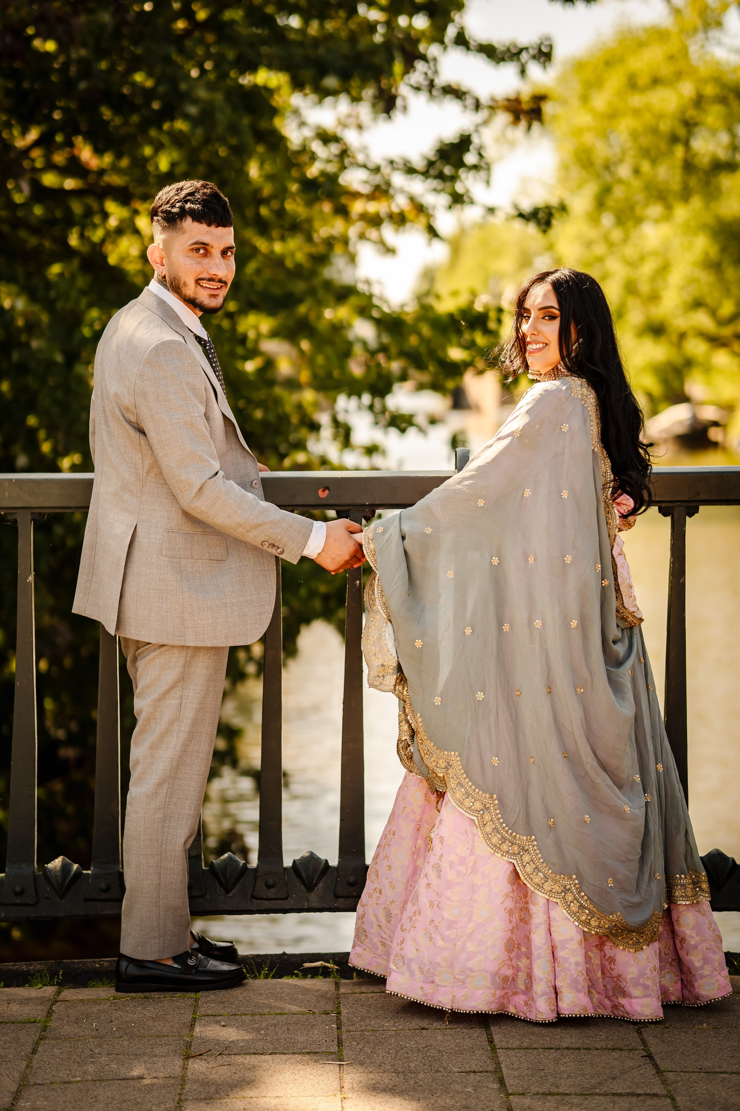 man holding hand of her bride and standing a canal bridge