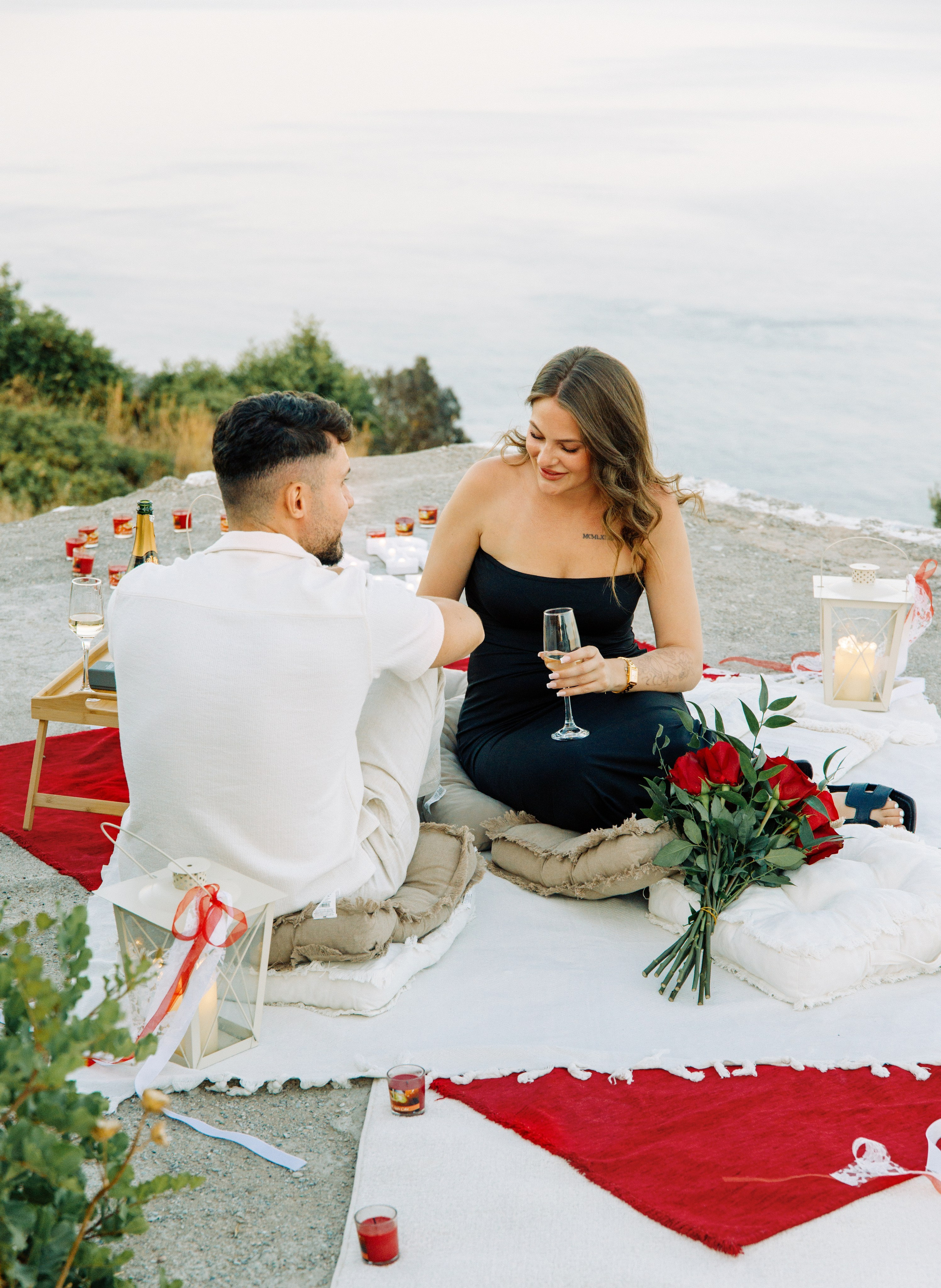 Marriage proposal in Rhodes 💍 couple at Profitis Ilias near Faliraki with red roses, candles and sea view at sunset in Greece.