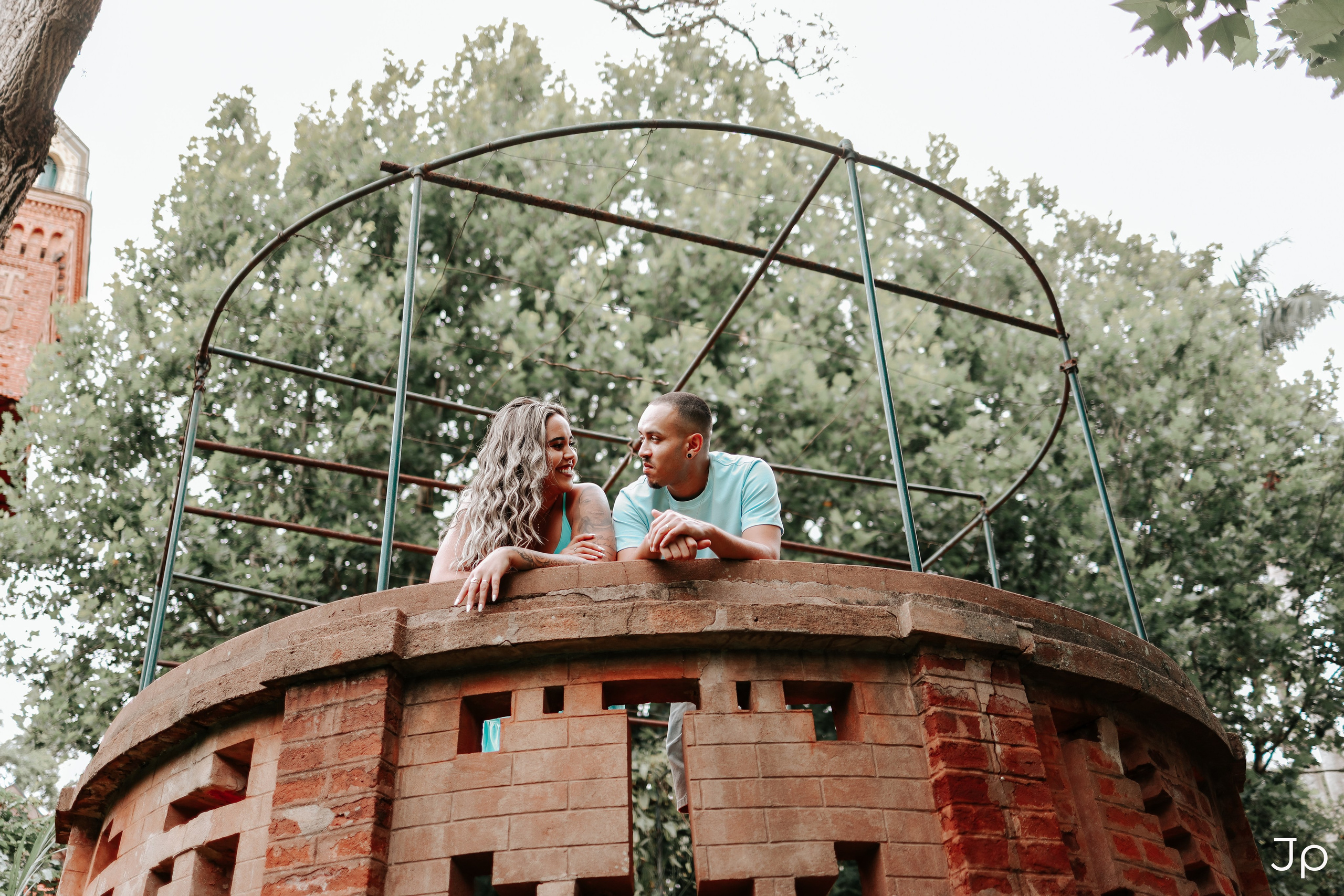 Ensaio pré-wedding no jardim com construção circular de tijolos, fotografado em Pederneiras.