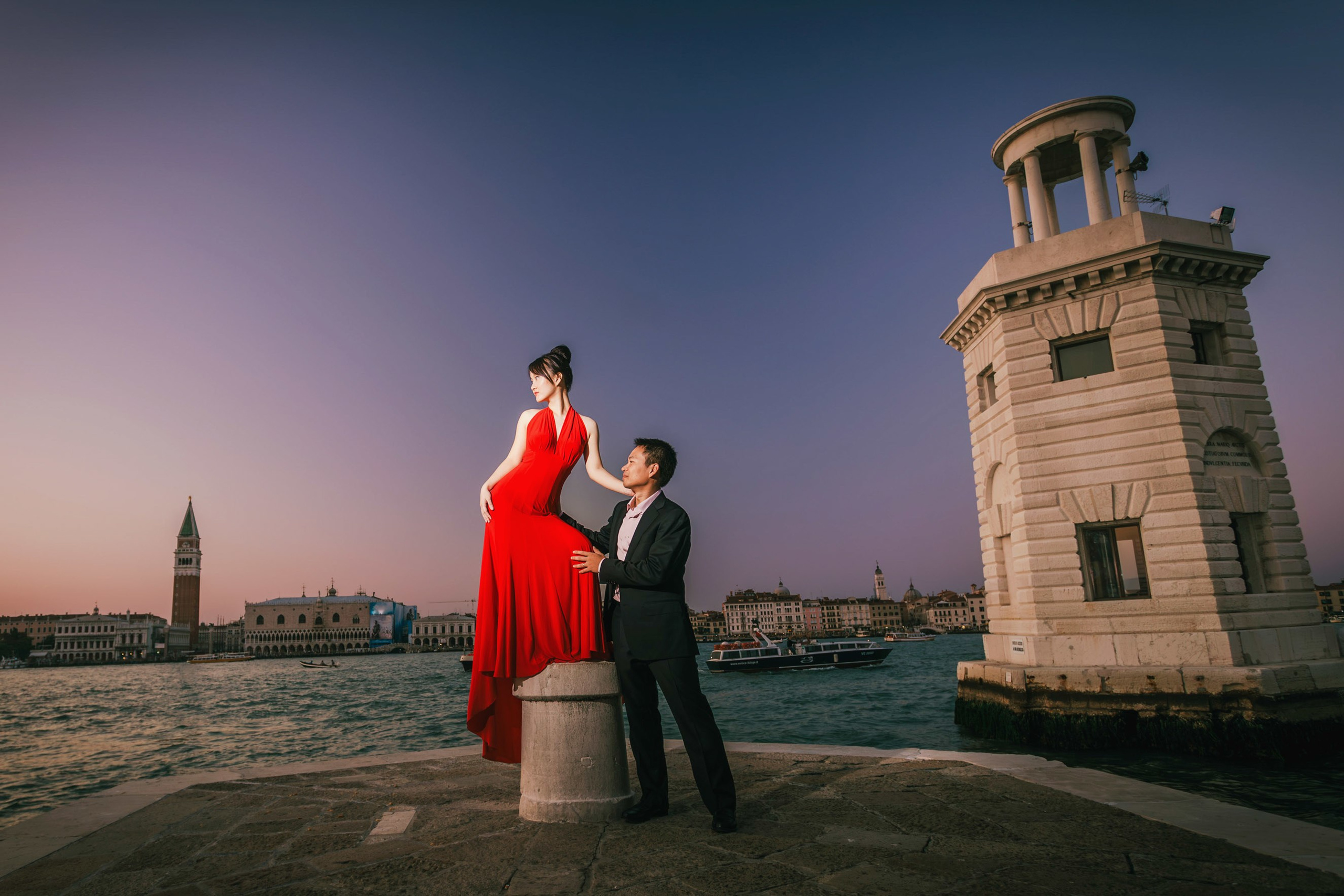 Dramatic portrait of stunning Thai woman in red dress posing in central Venice.