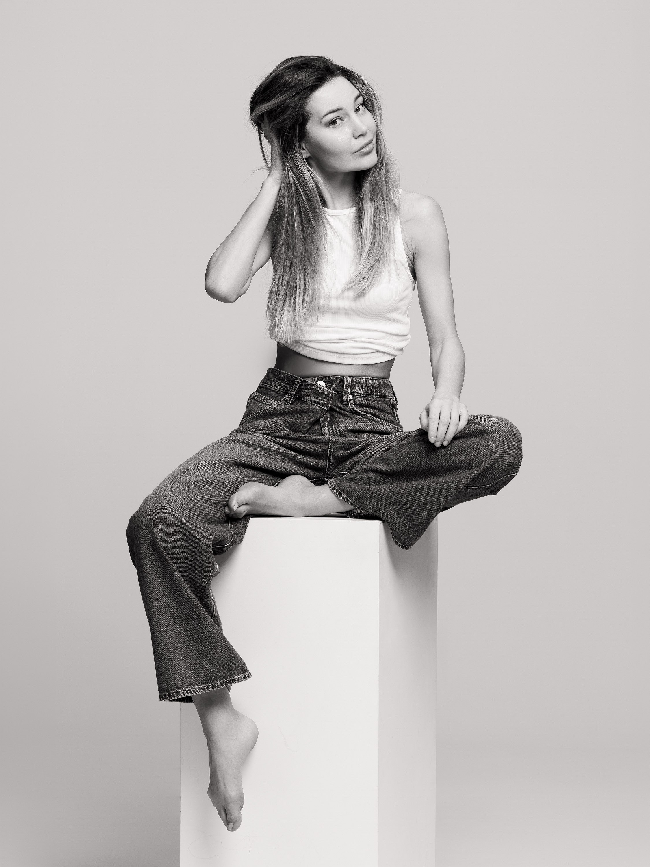 teenage girl leaning back on a studio cube, black and white portrait