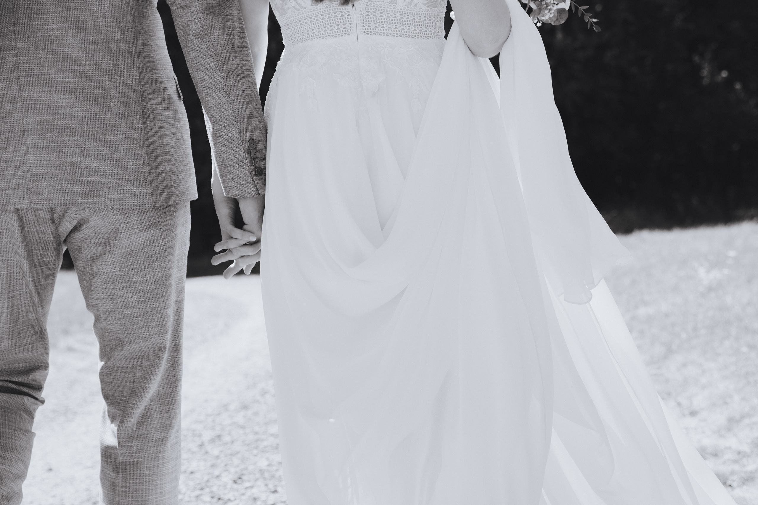 Der Bräutigam und die Braut gehen Händchen haltend spazieren.