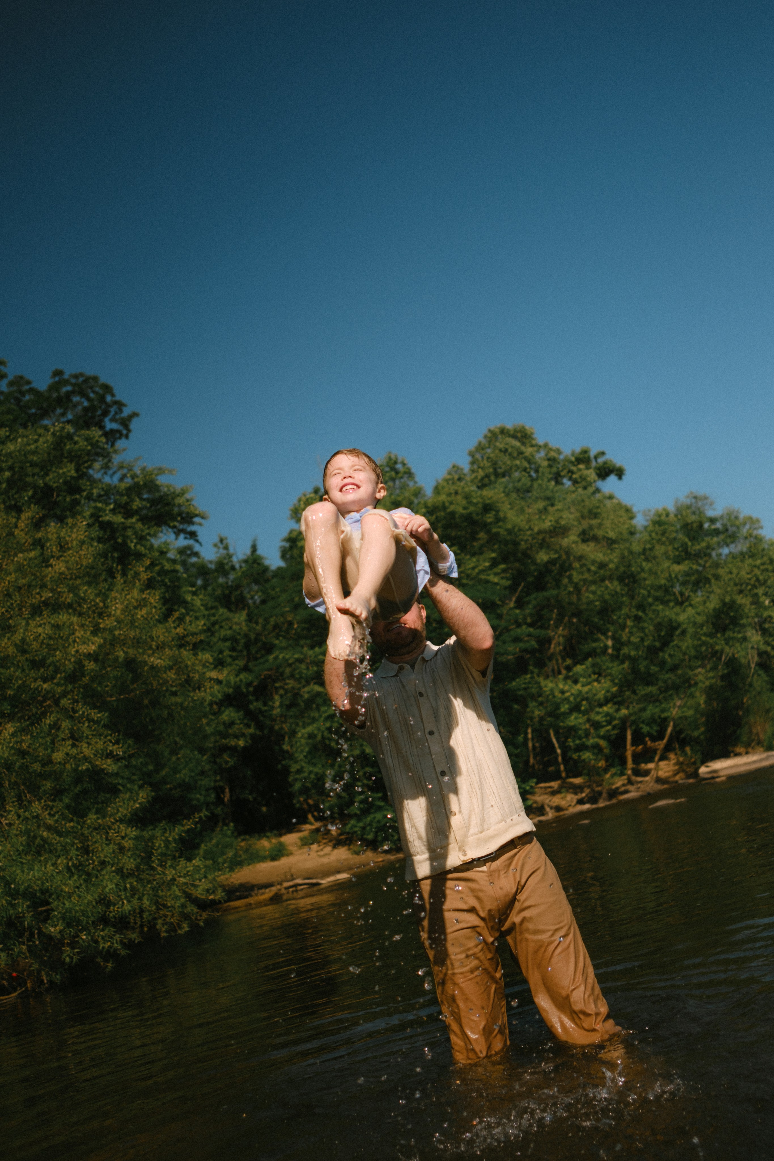 Documentary family photographer capturing candid, unposed moments of kids splashing in the James River water