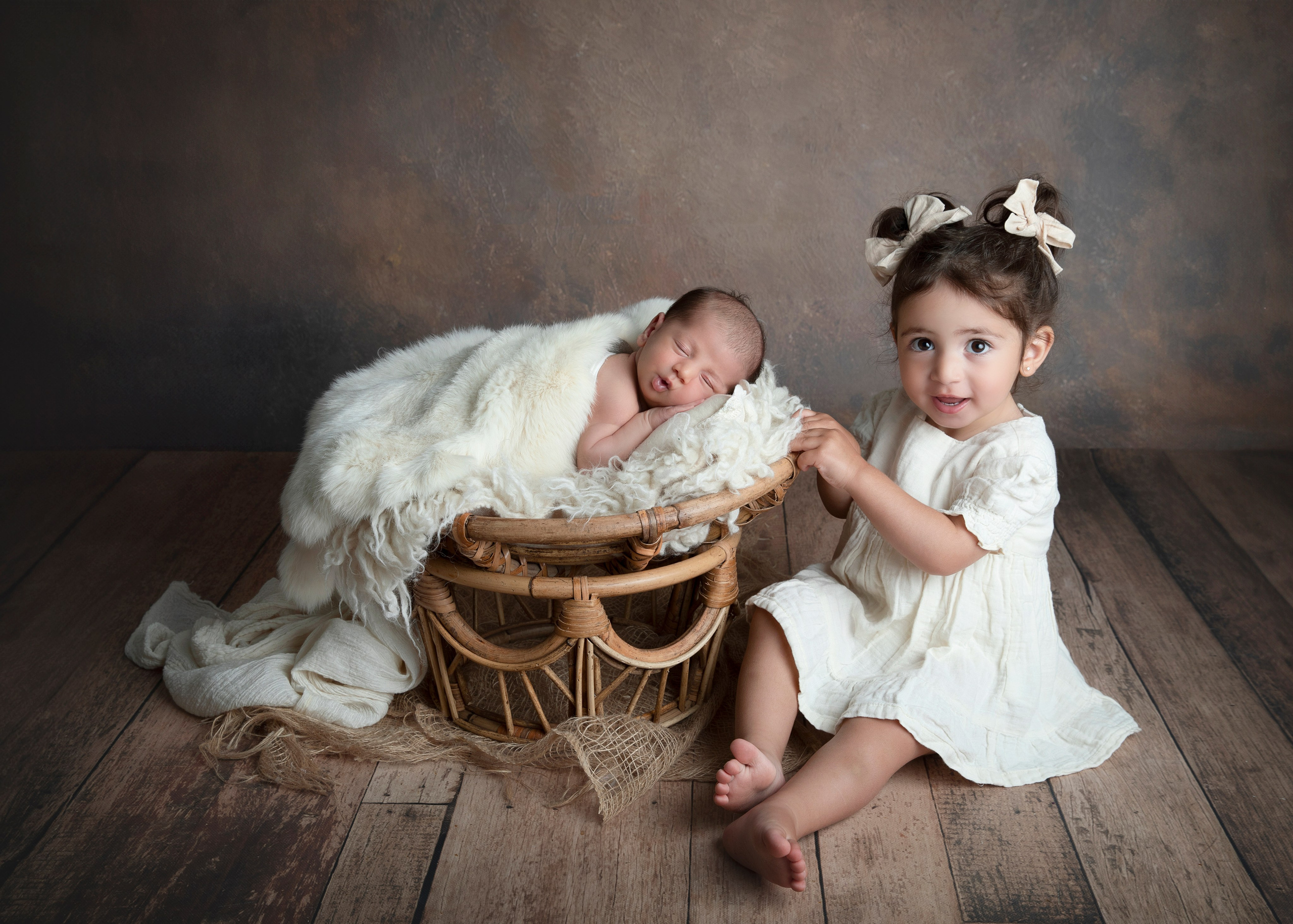 Syskonen håller sin nyfödda bror i famnen, ett fotografi från fototillfället av familjeband och glädje.