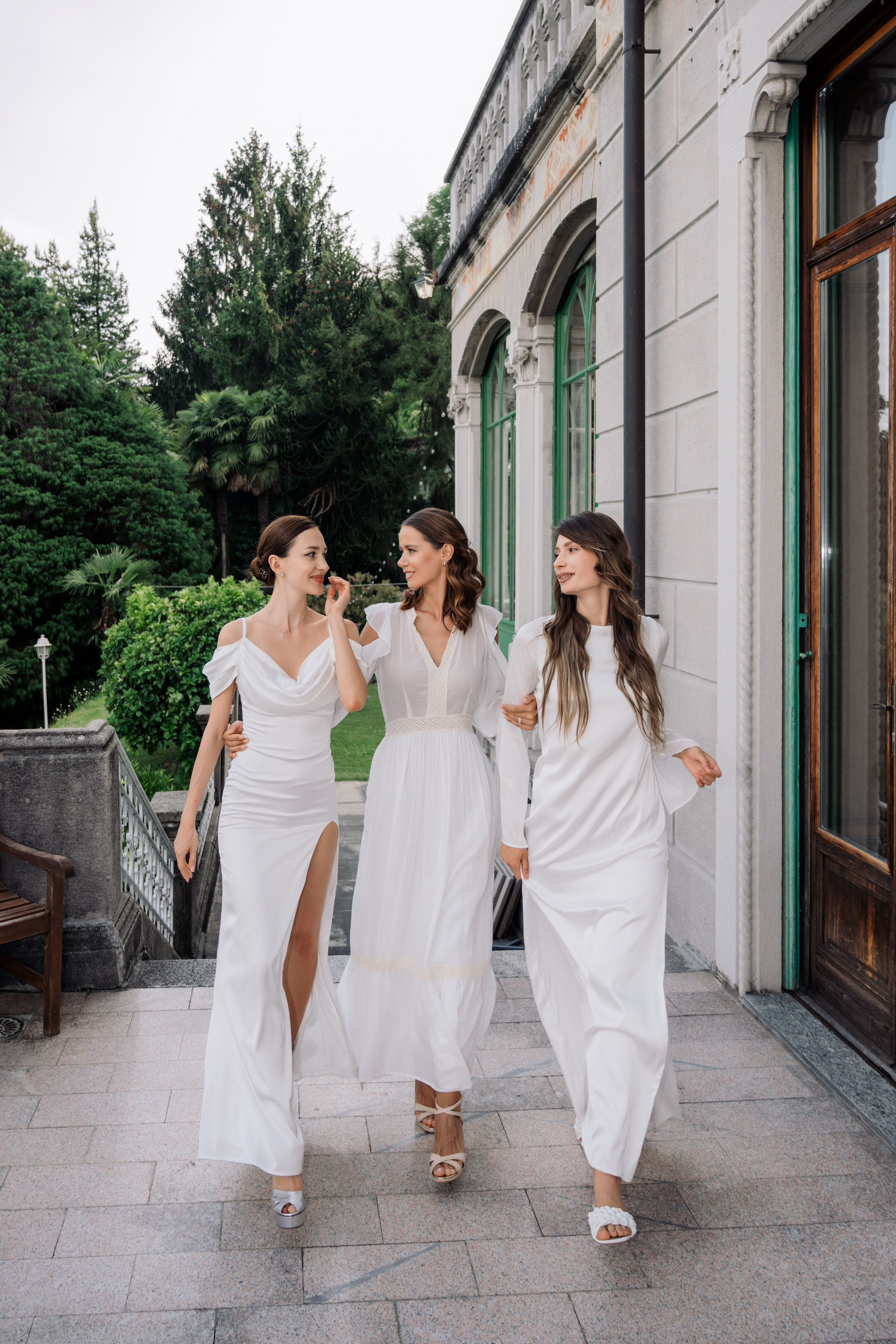 three women in white dresses walking down a sidewalk