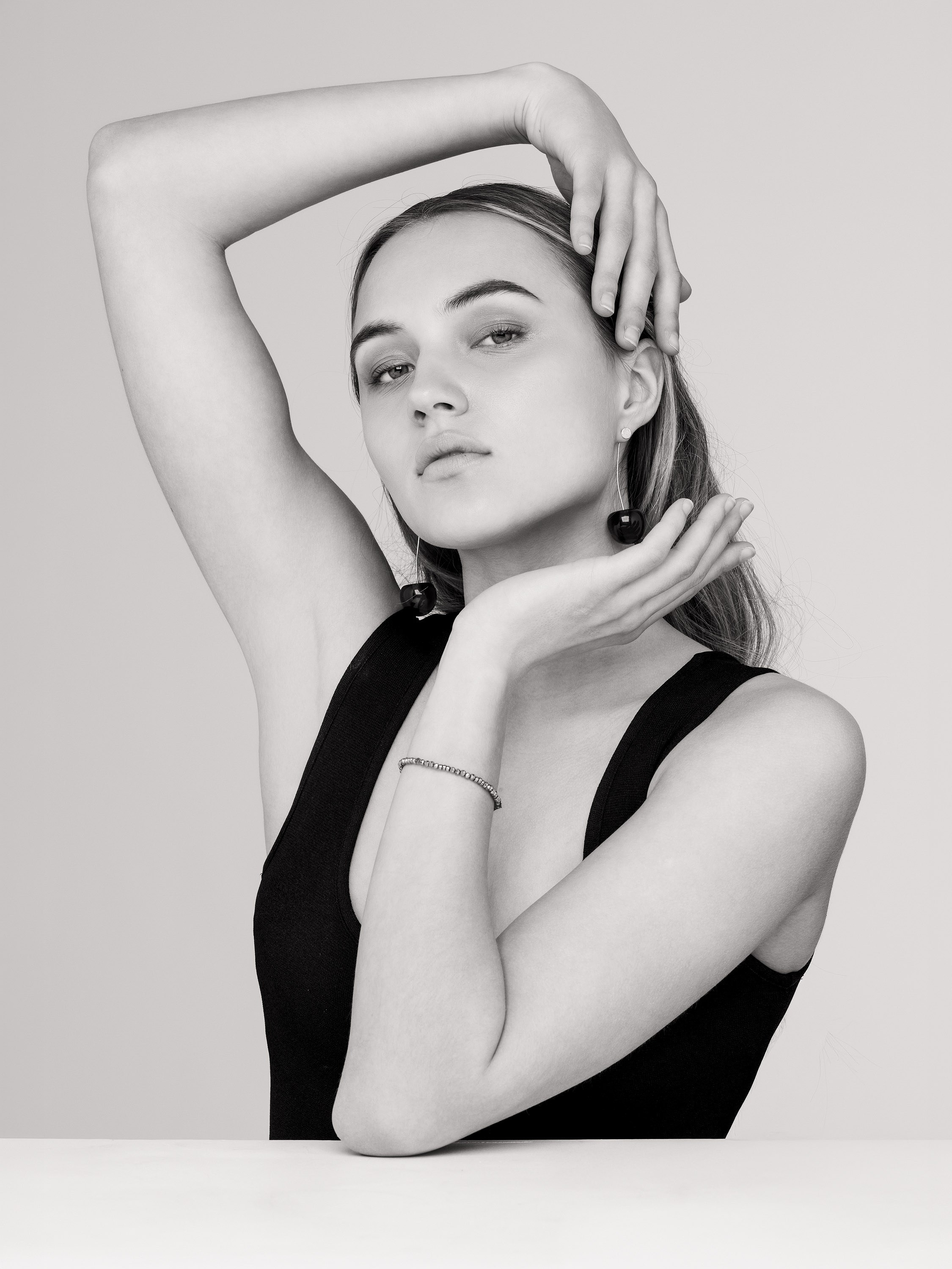 woman in a studio fashion portrait, hand resting above her head, black and white