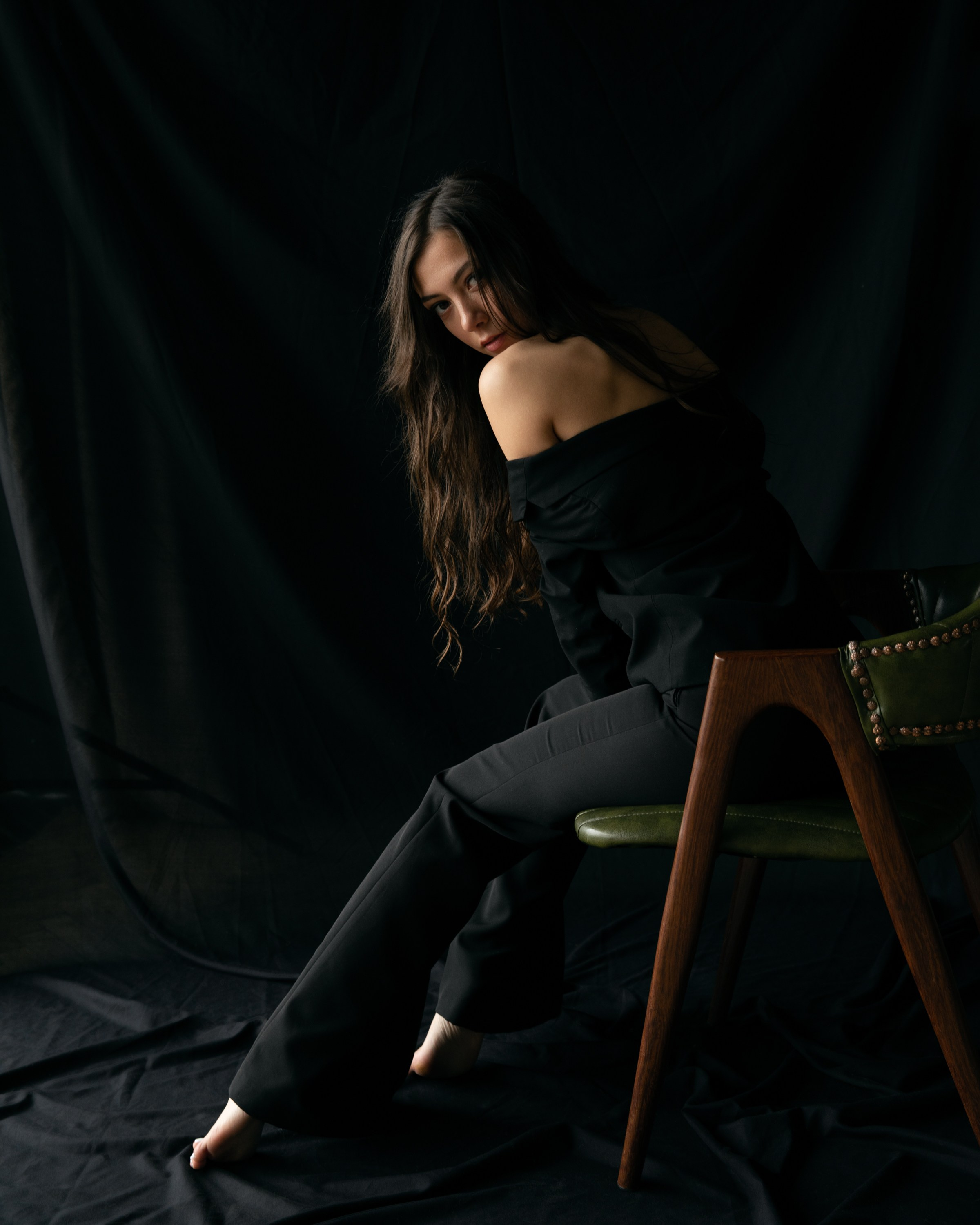 Elegante Frau barfuß in Schwarz auf grünem Stuhl