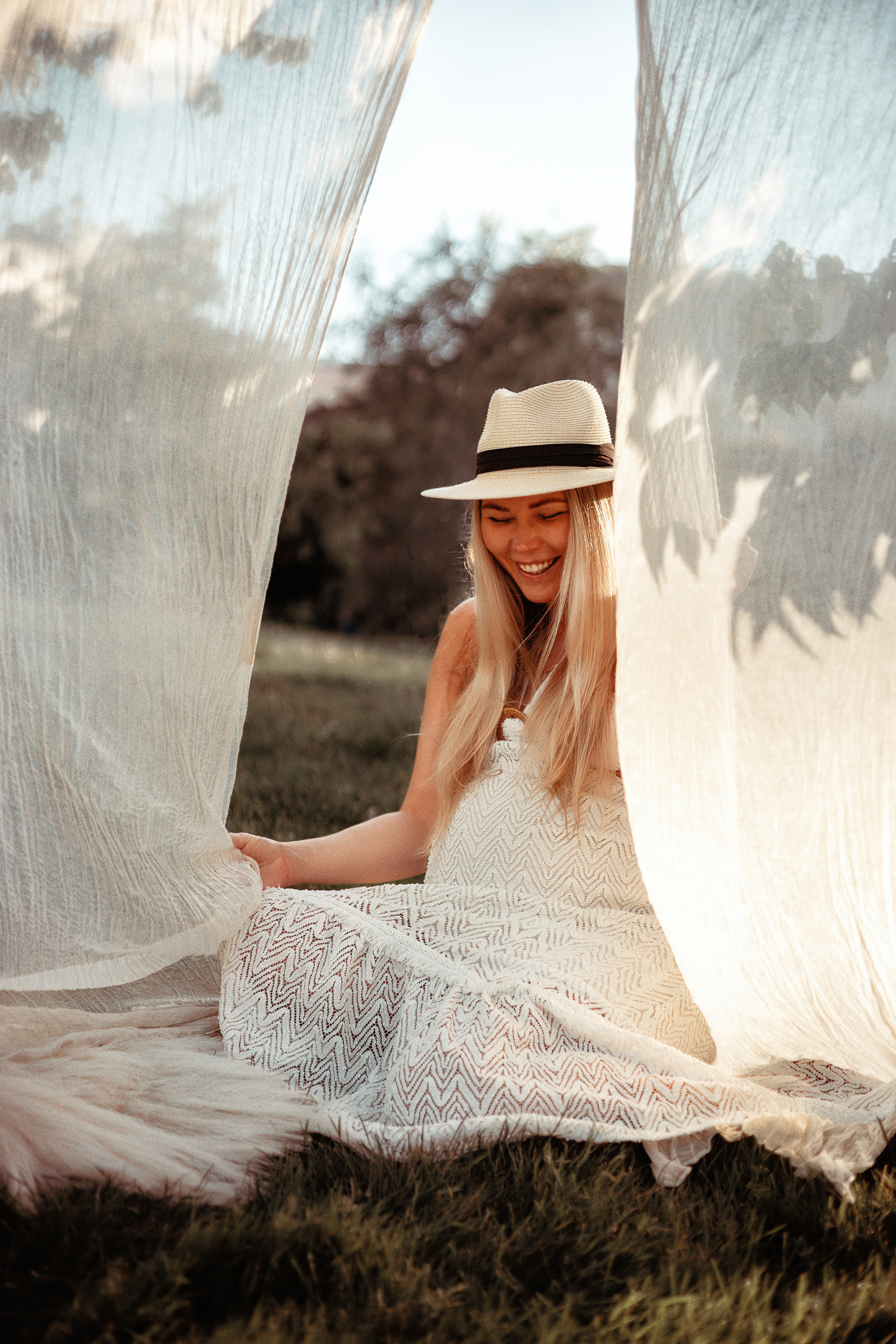 Pregnant woman sitting on the grass in the shade of trees