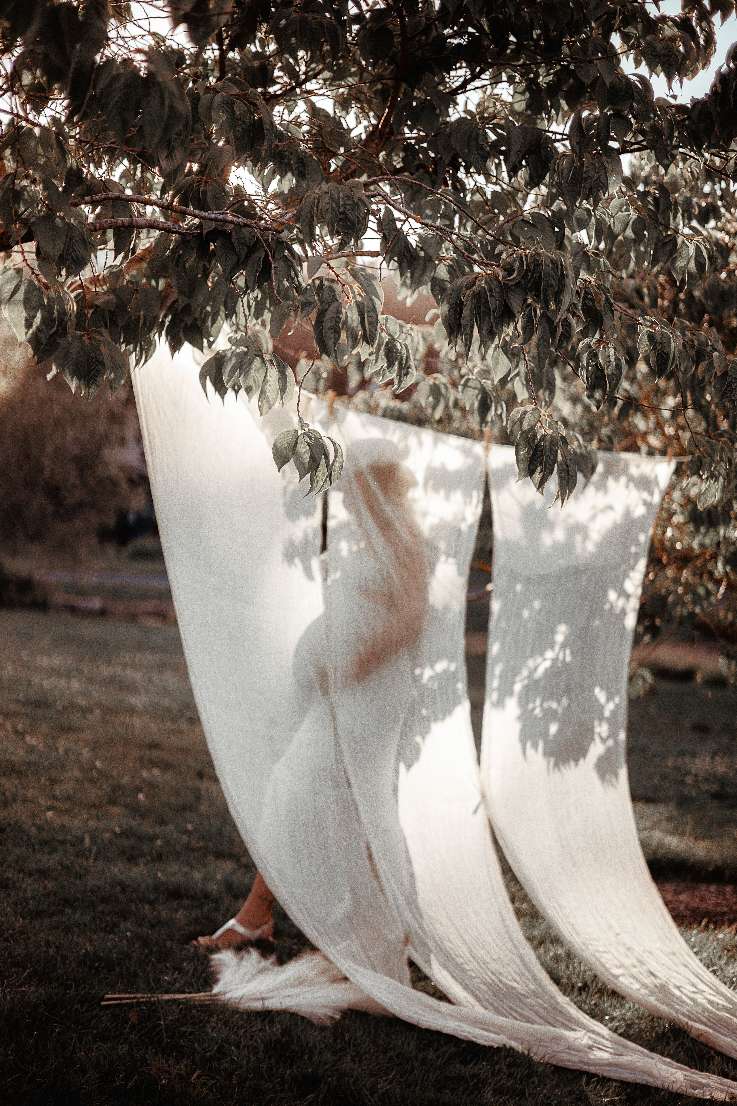 Expectant mother smiling while standing on a bridge in the forest
