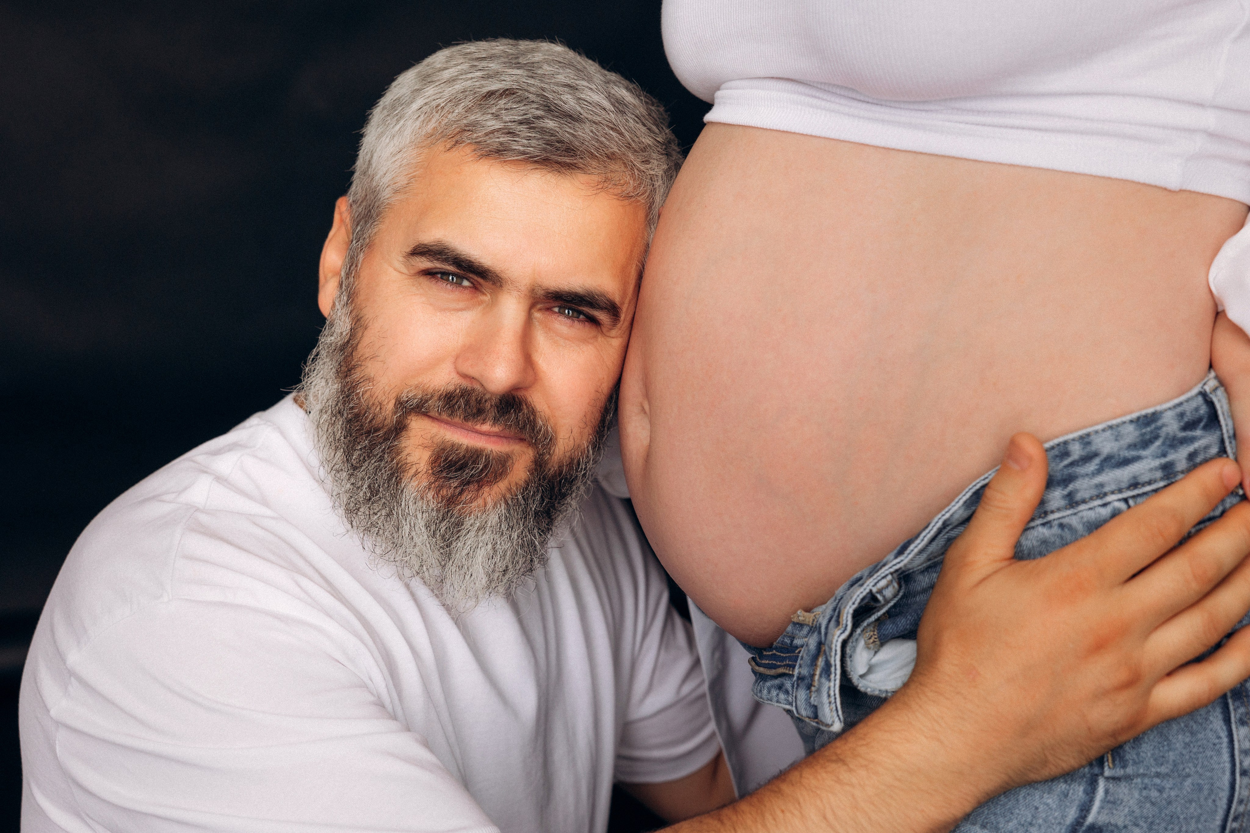 Para w oczekiwaniu – kobieta opiera się o partnera, pełna zaufania poza i delikatność relacji.